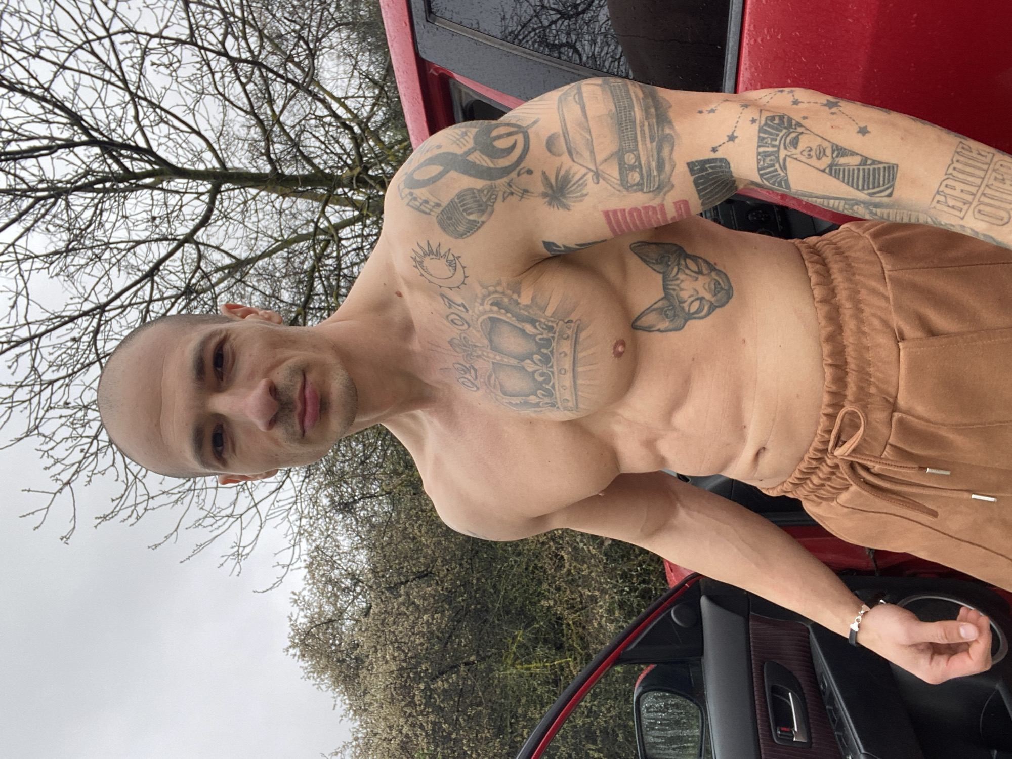Tattooed man photographed with red car in Pleven