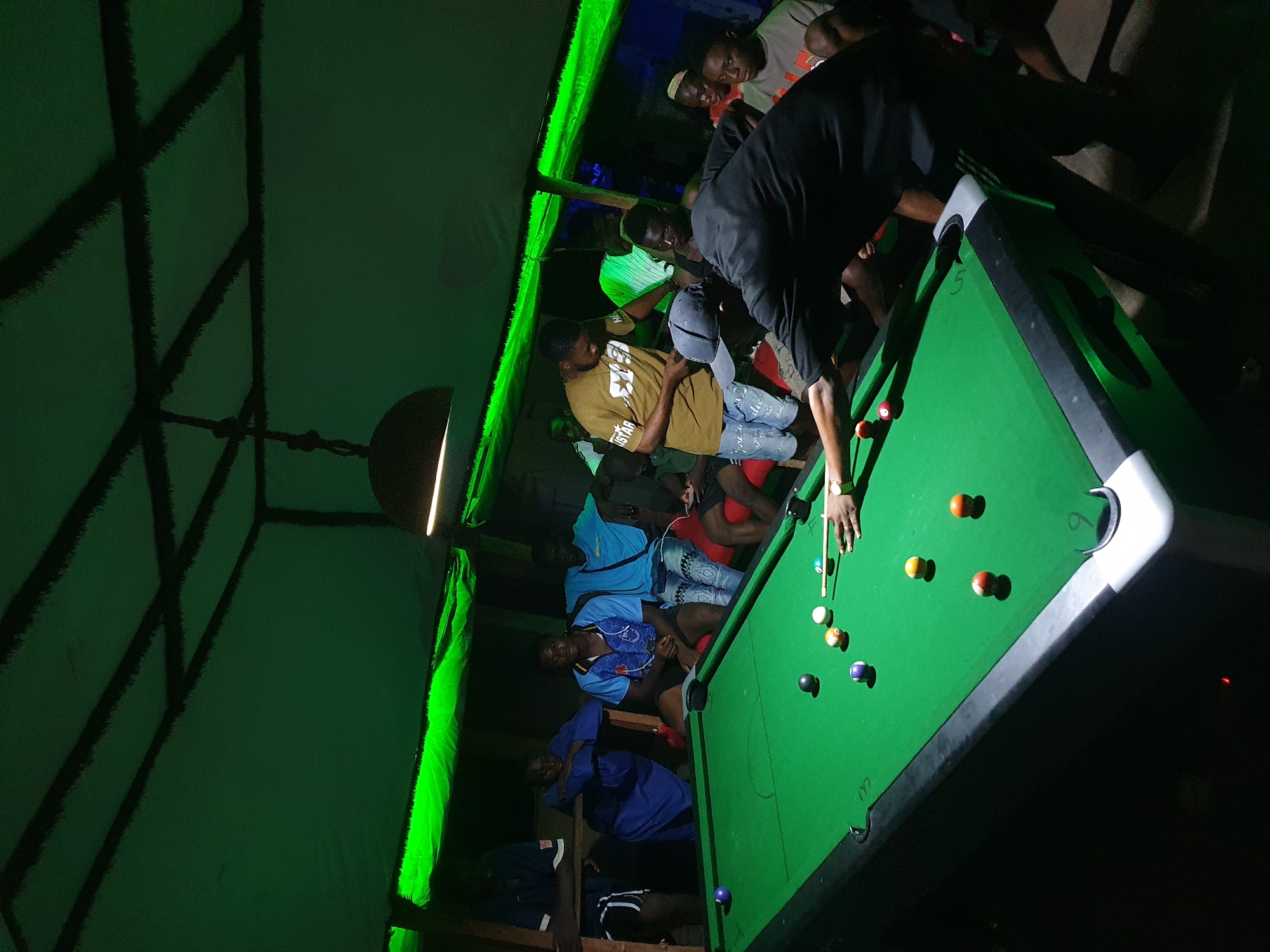 Young men play pool at nighttime venue in Lokoja
