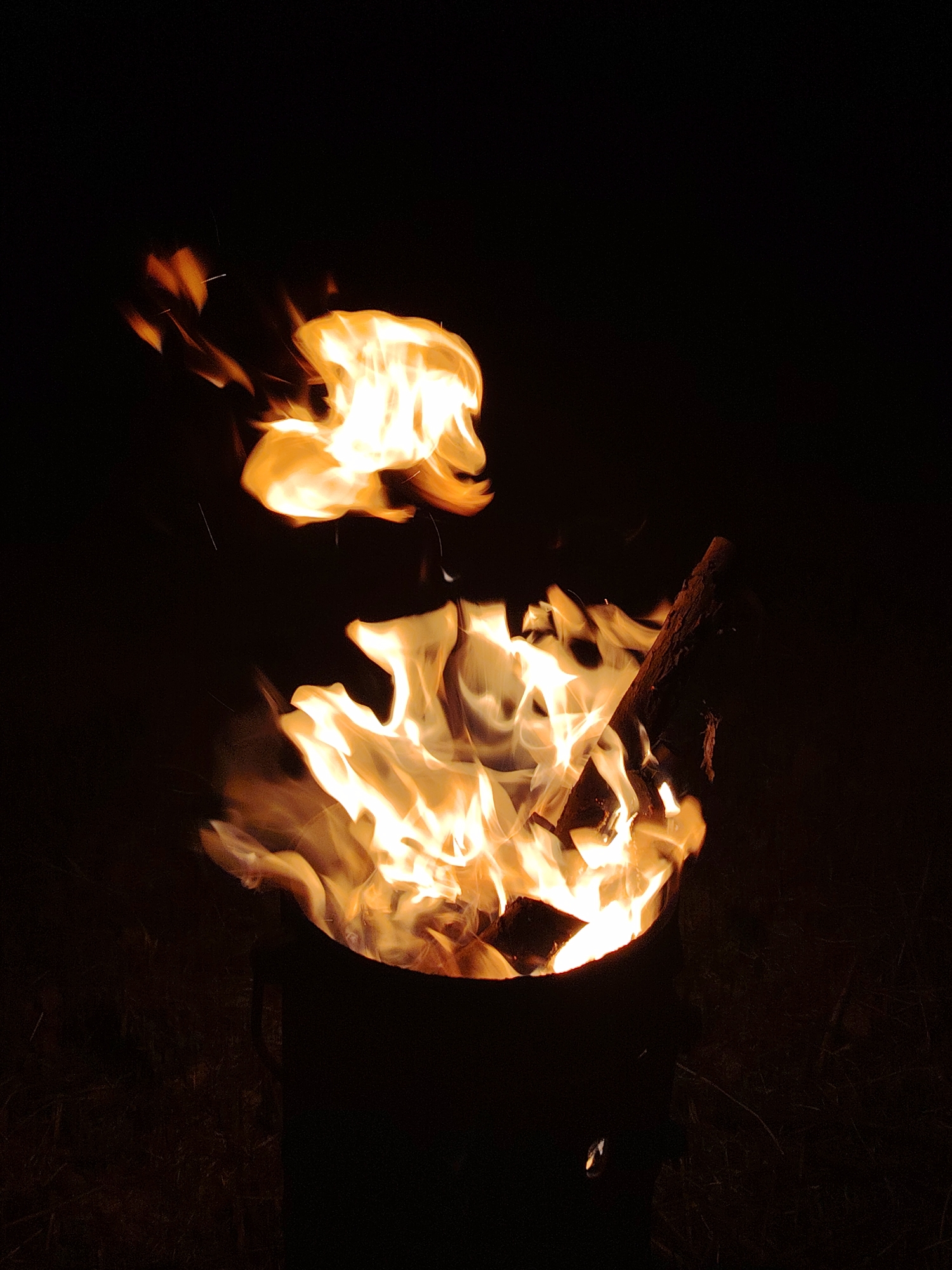 Bonfire burning in a metal receptacle at night