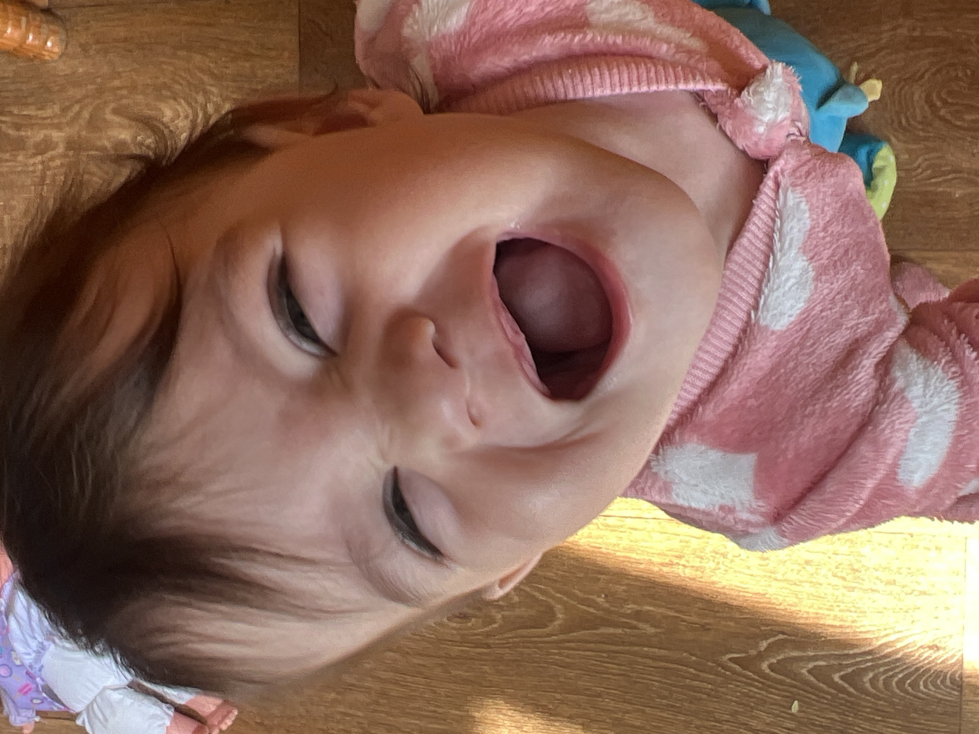 Baby photographed in pink outfit on wooden floor in Elena