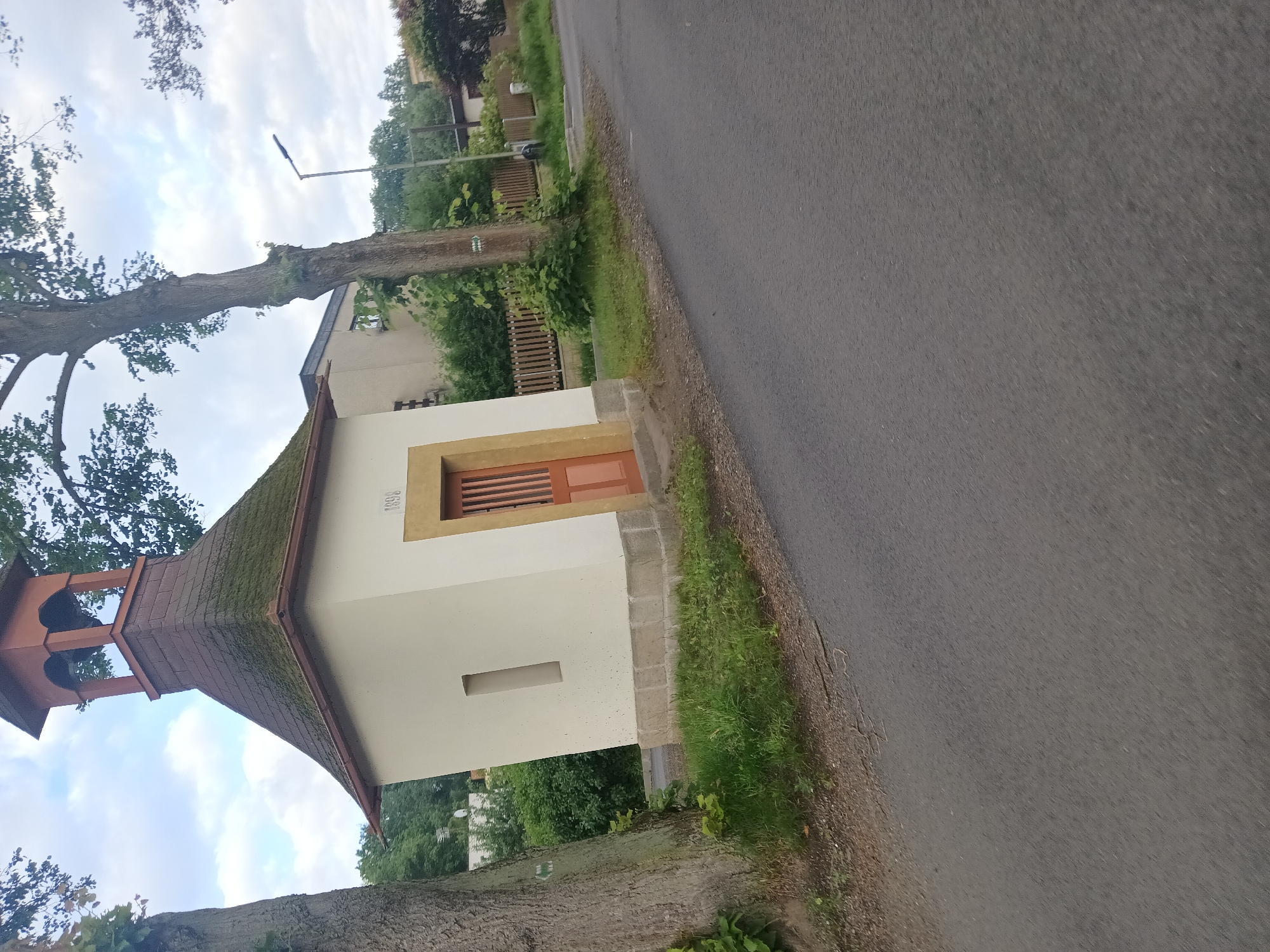 Rural Czech village road with chapel, log house, and local beer banner