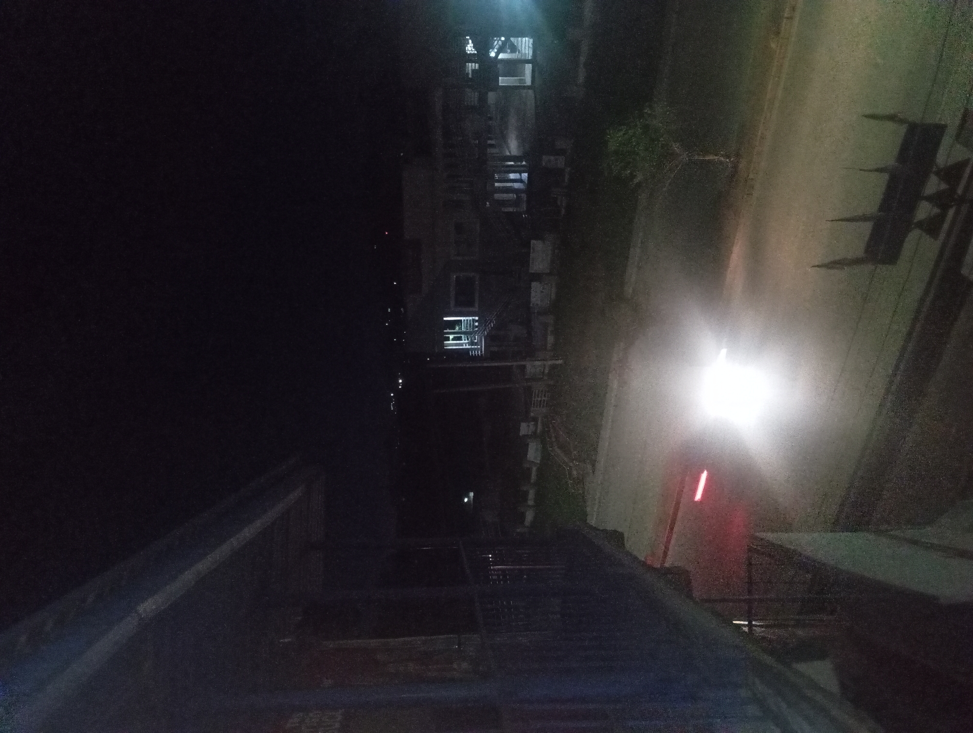 Vehicle travels nighttime street near illuminated modern building
