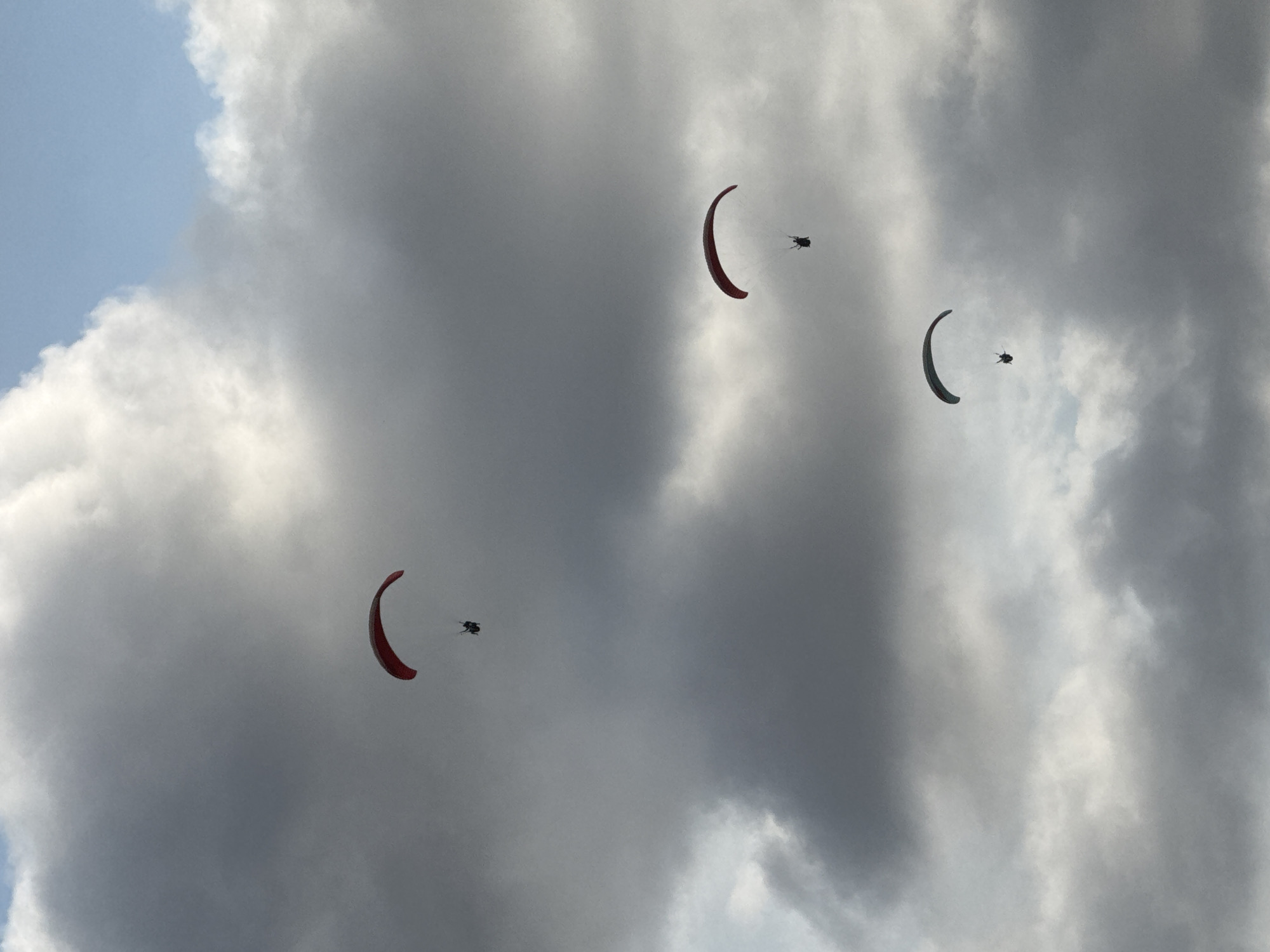 Paragliders, paddlers, and beachgoers fill a Bali coastal morning
