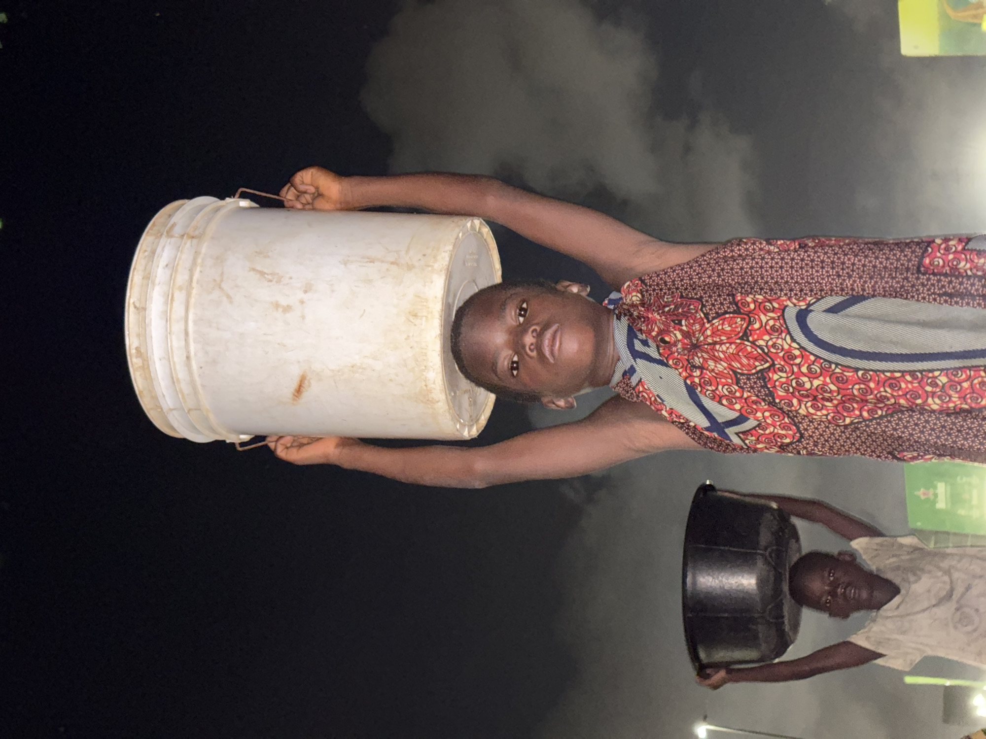 Two people carry buckets on heads in Lagos
