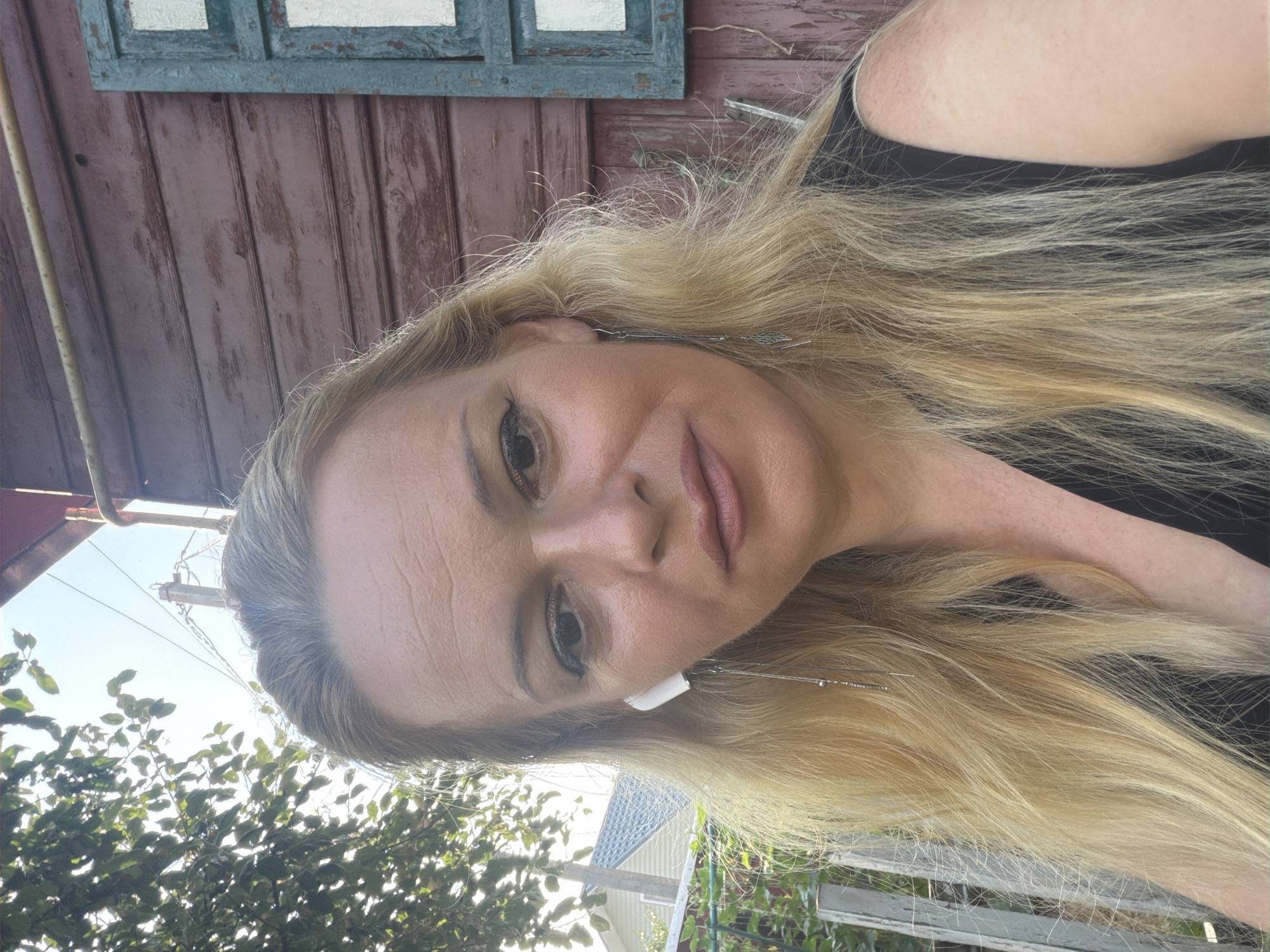 Multiple selfie attempts outdoors near a rustic wooden wall