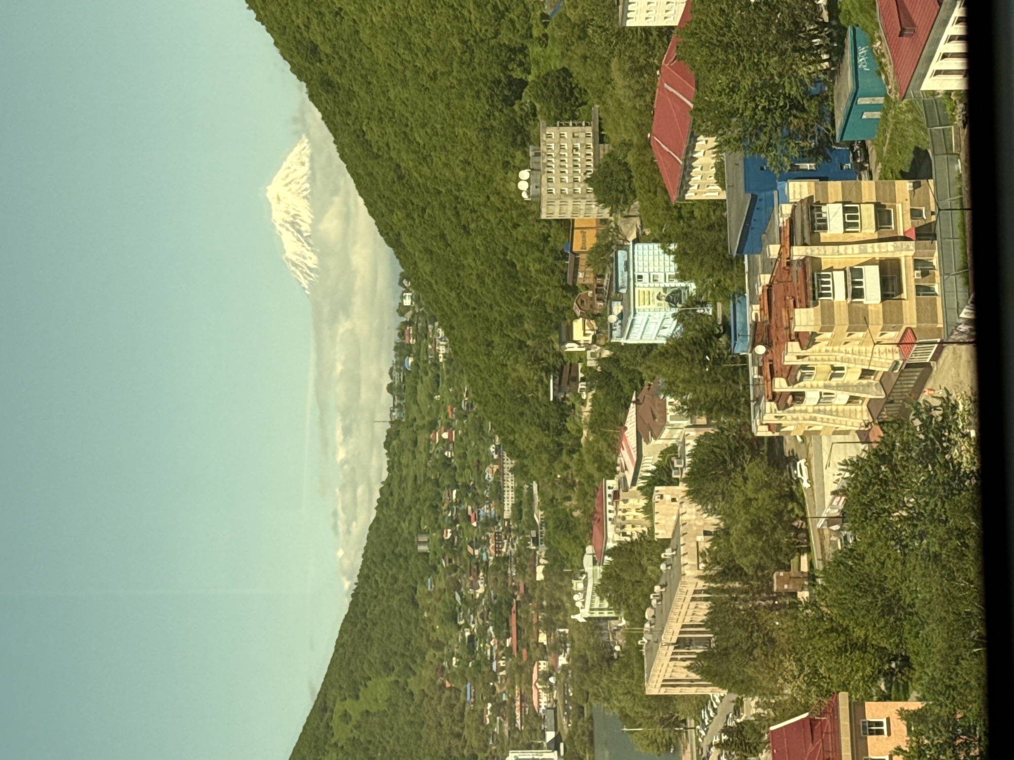 Snow-capped volcano towers over a hillside town in a green valley