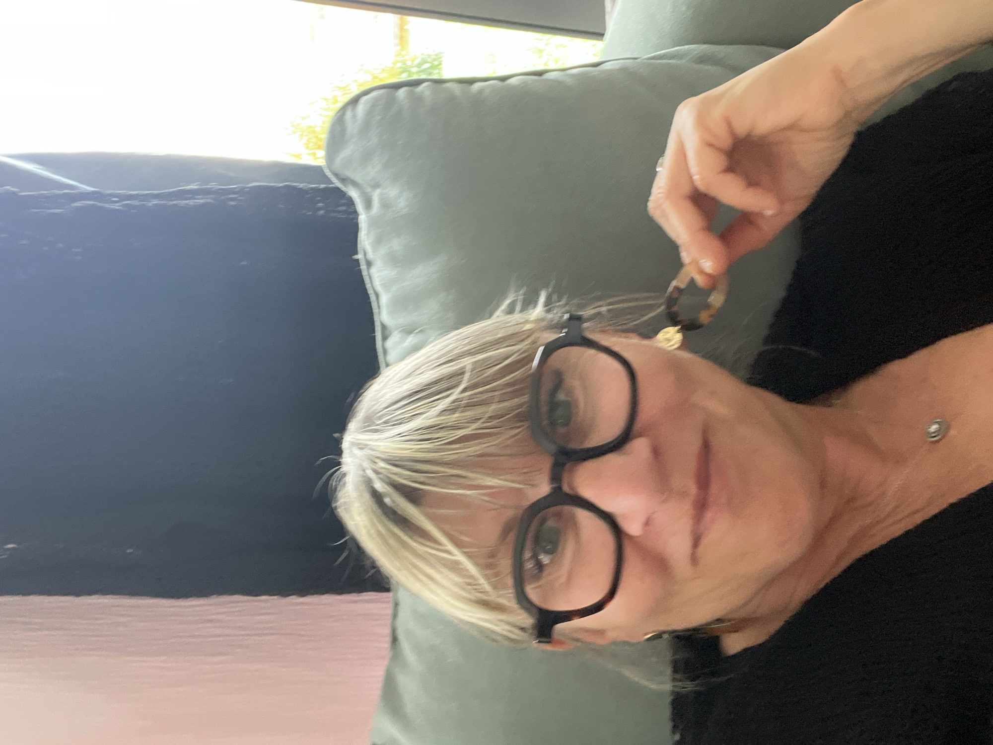 Woman displays tortoiseshell earrings indoors in Chambœuf