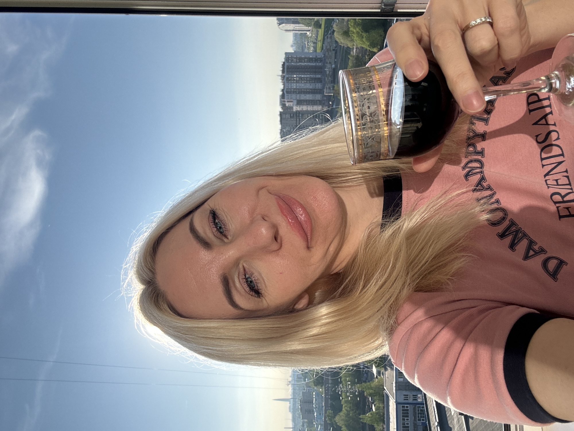 Woman enjoys wine on city balcony during sunny afternoon