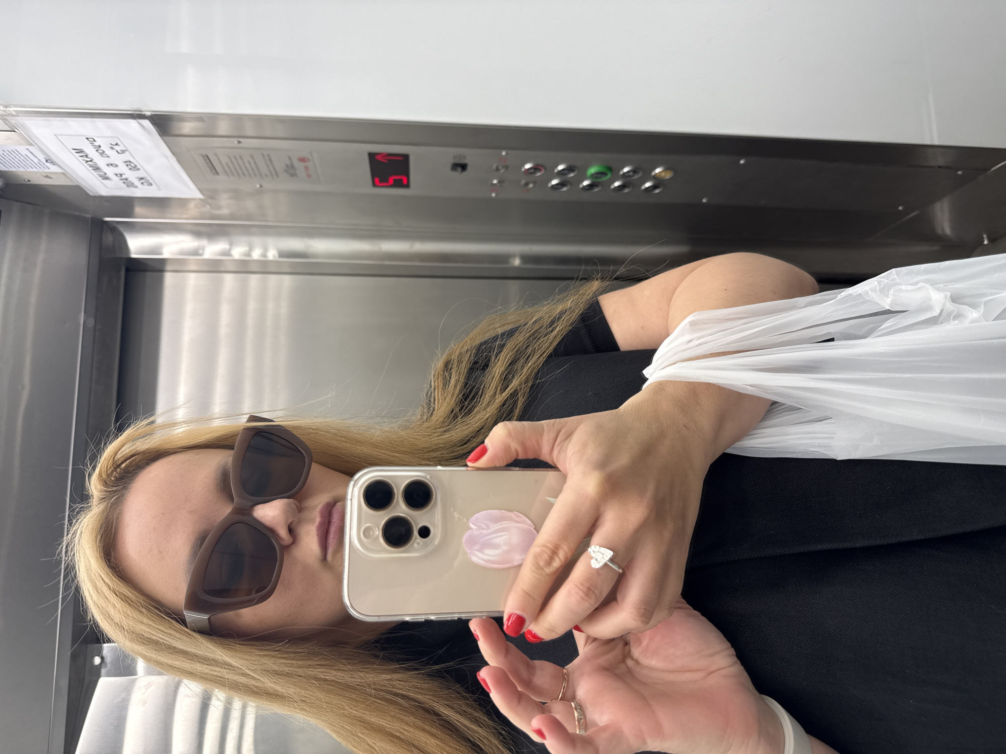 Woman photographs selfie and jewelry in Tel Aviv elevator