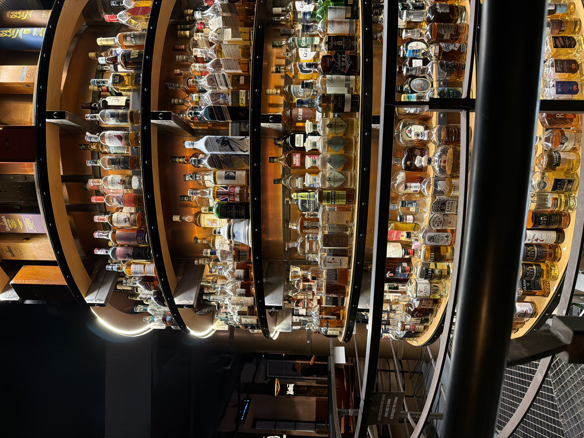 Warm-lit bar shelves packed with whiskey bottles on display