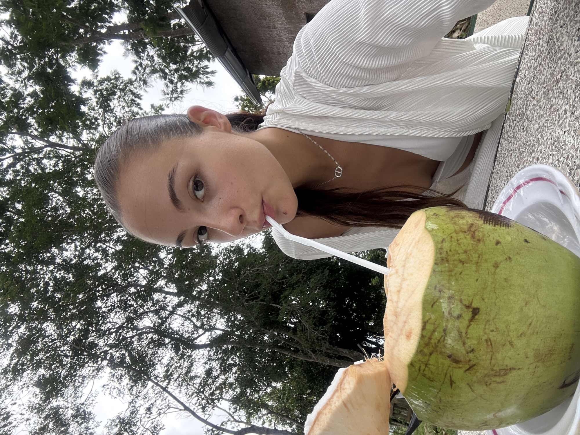 Woman enjoys coconut drink at beachside café in Karon