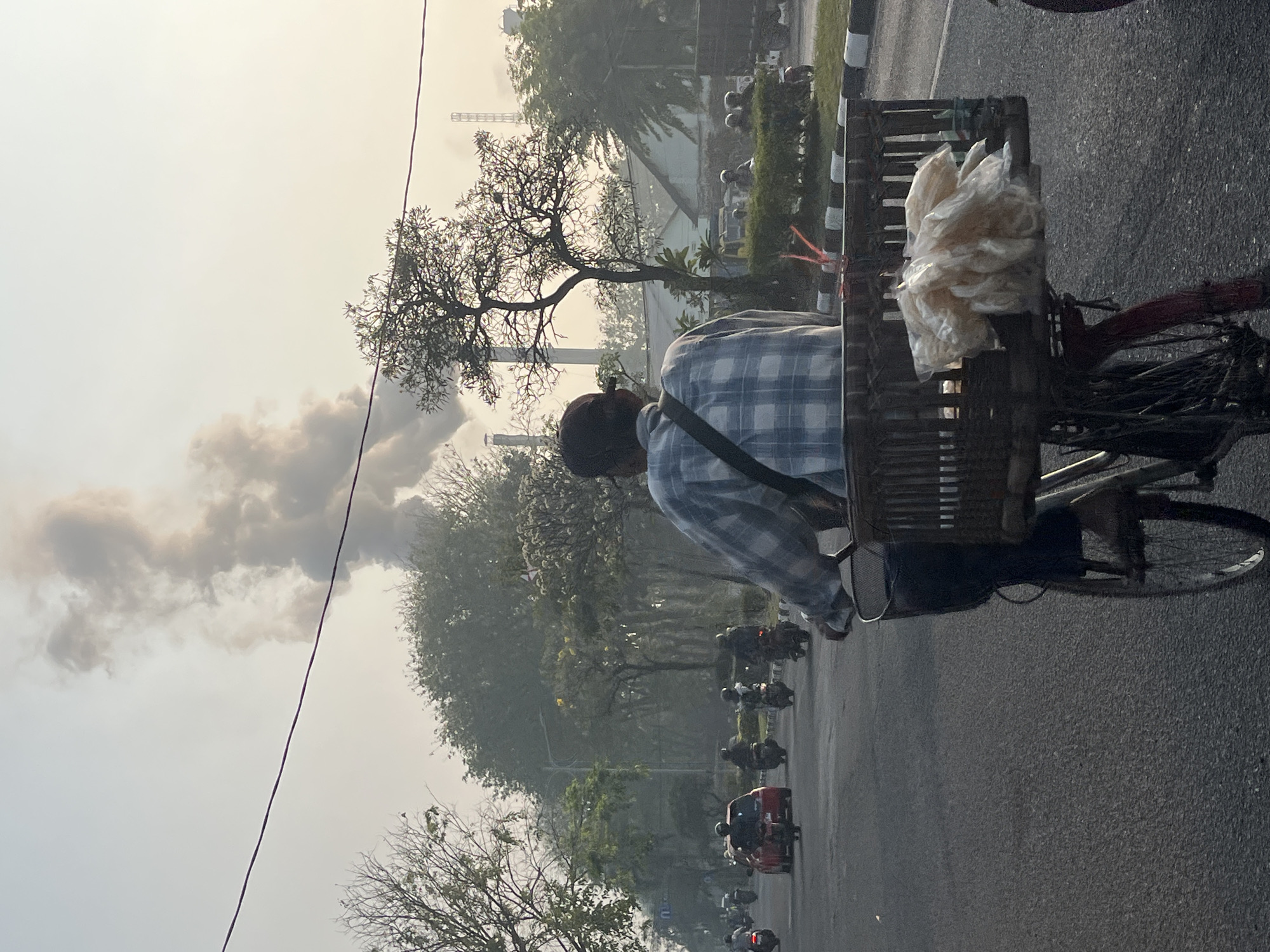 Industrial smoke hangs over busy Candi streets as traffic moves through