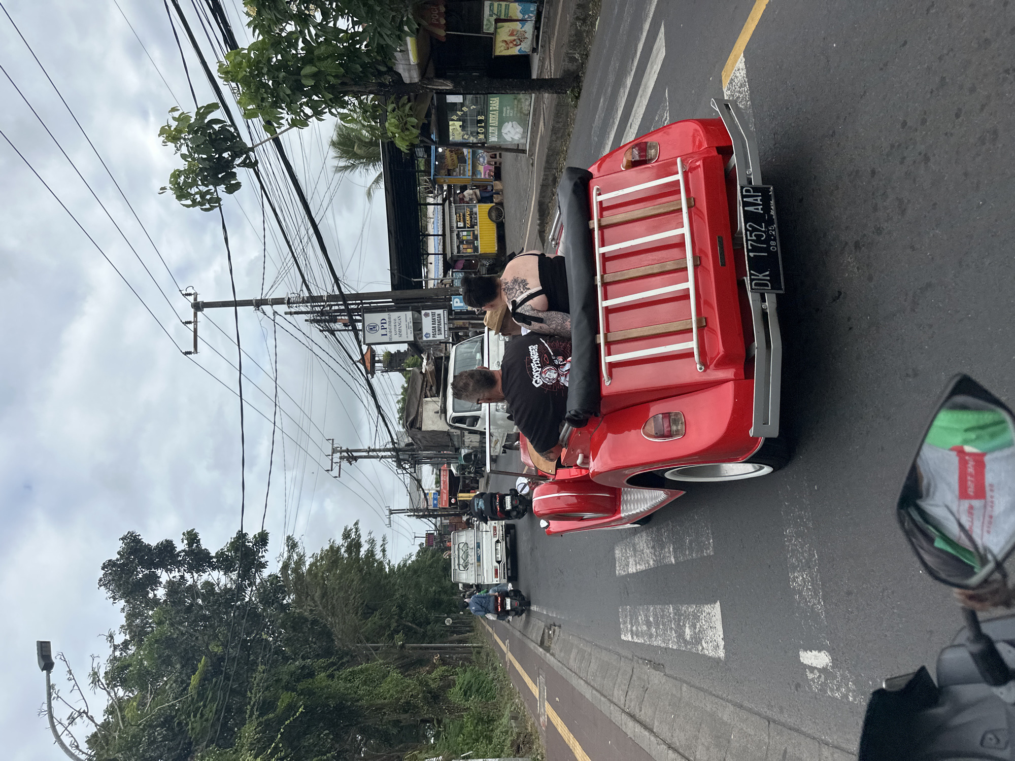 Red convertible cruising through cloudy Kuta Selatan streets