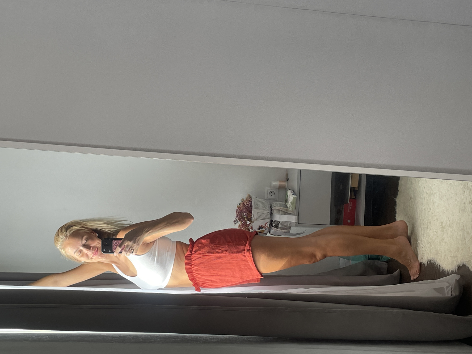 Woman photographs herself in bedroom during early morning session