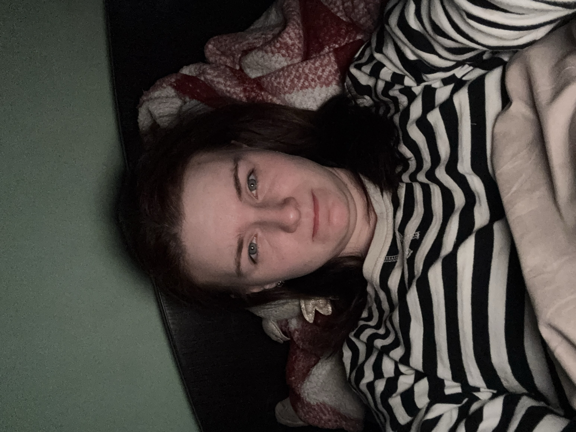 Woman rests indoors wearing striped shirt, location unknown