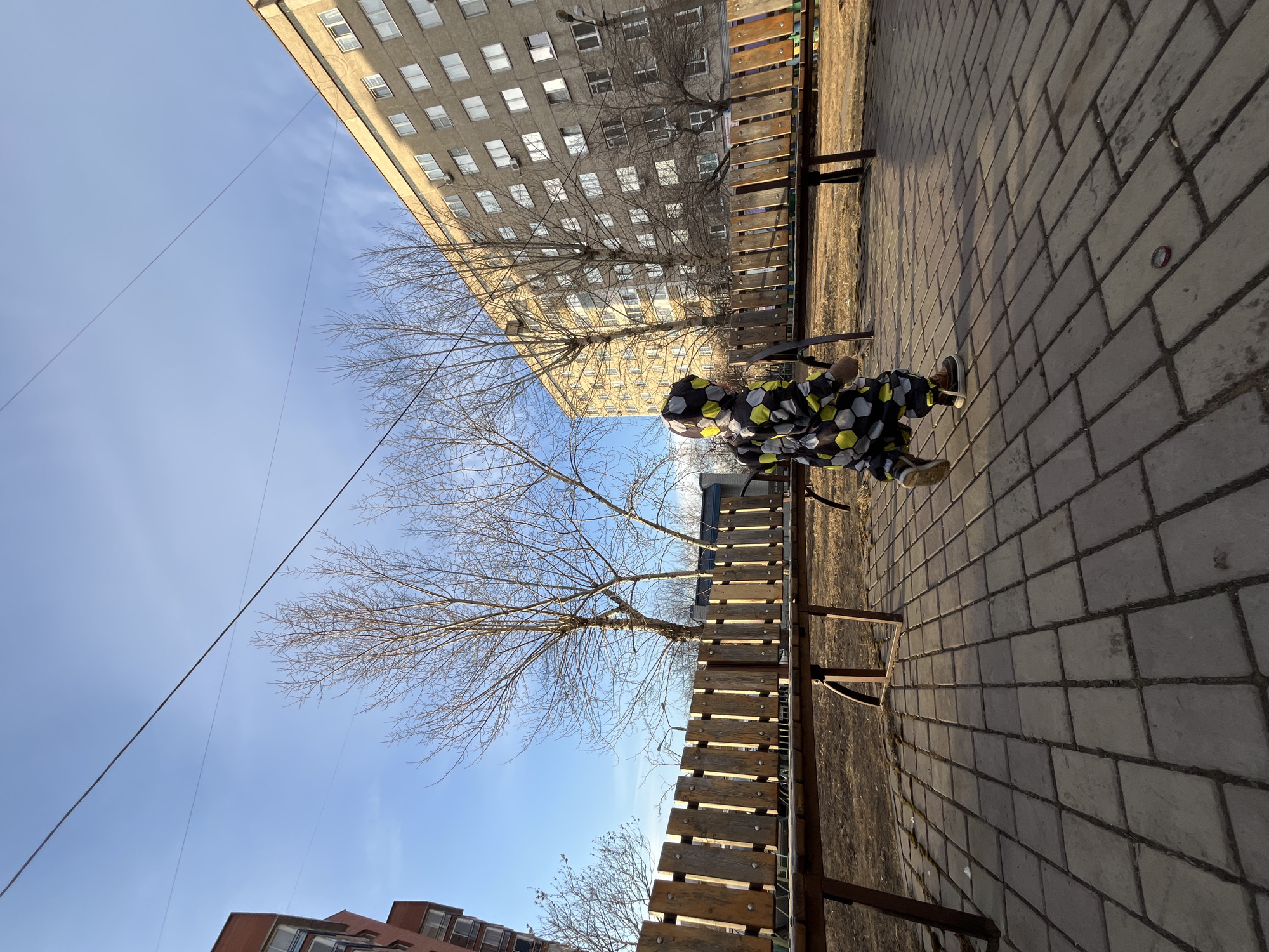 Person photographed on park bench in Krasnoyarsk urban setting
