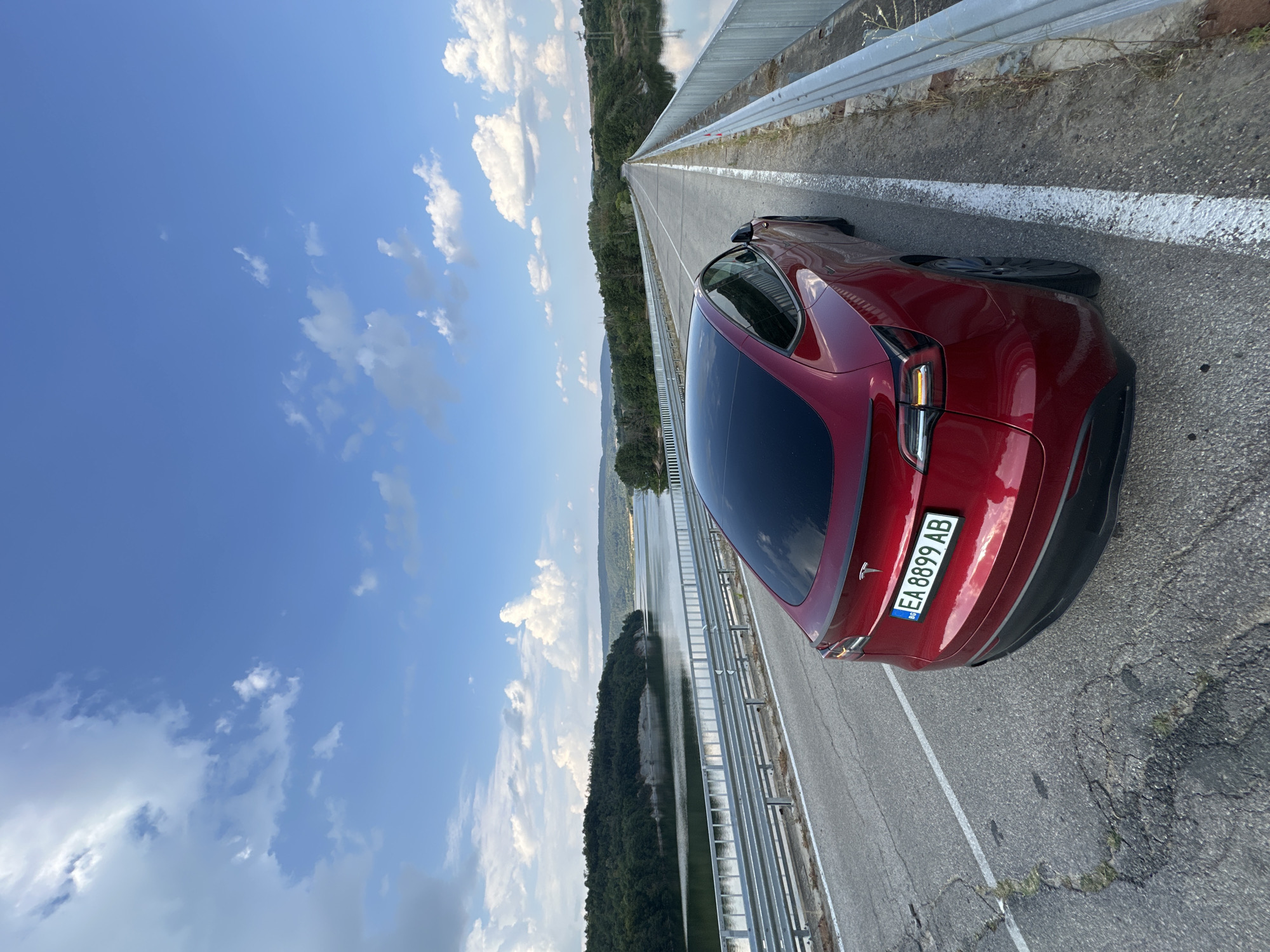 Red Tesla parked by a quiet reservoir in rural Bulgaria