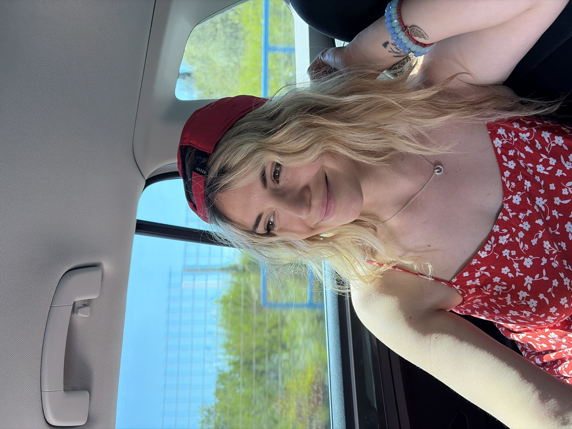 Woman in red cap photographed smiling in car, Tivat