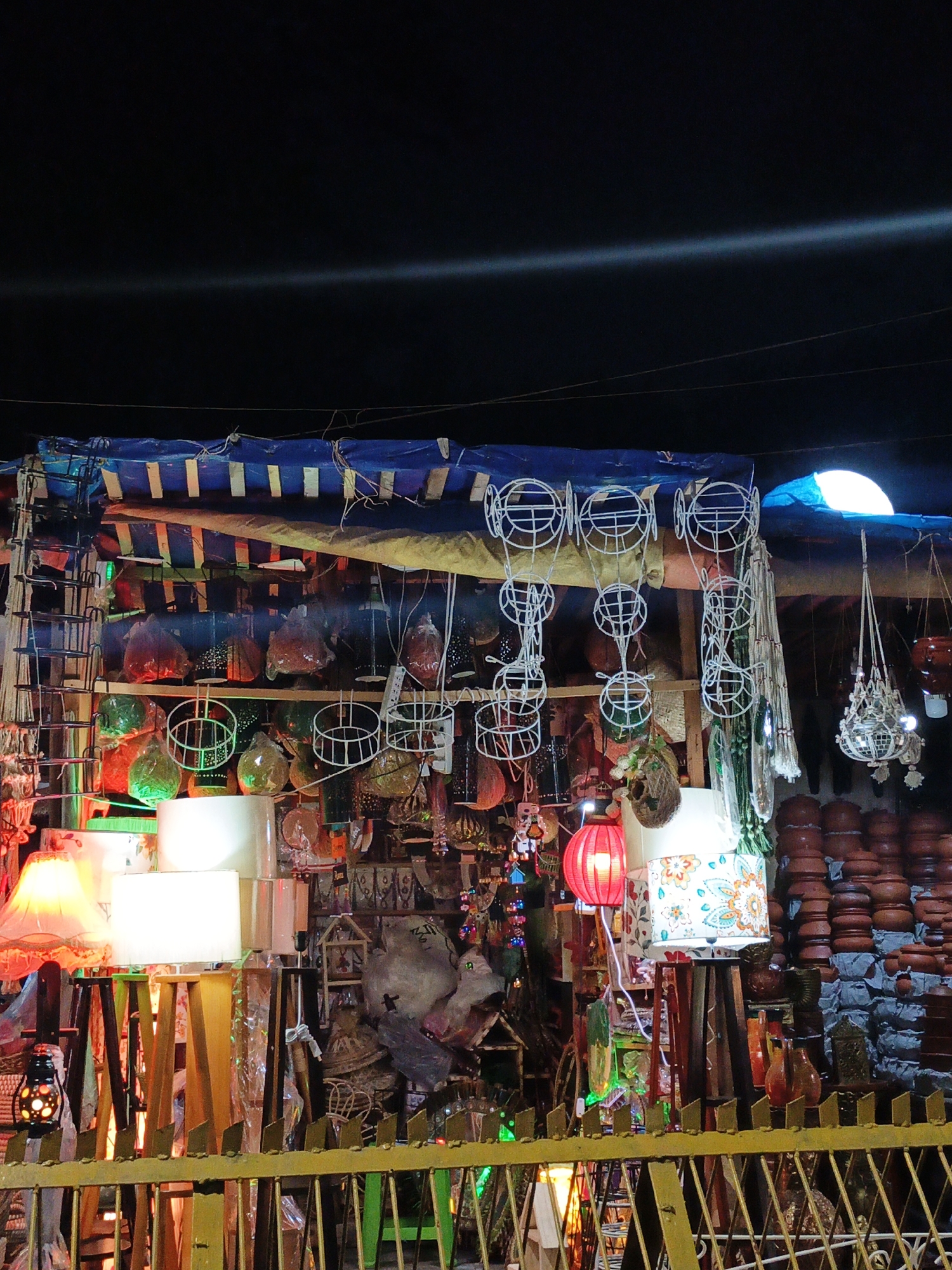 Night market with lamp stall, parked motorcycles observed