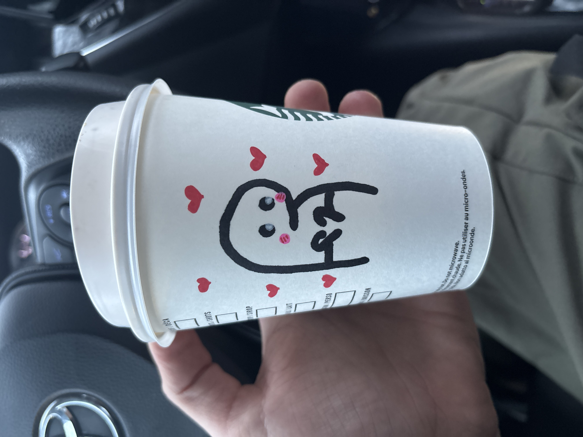 Customer holds decorated Starbucks cup with cartoon heart design