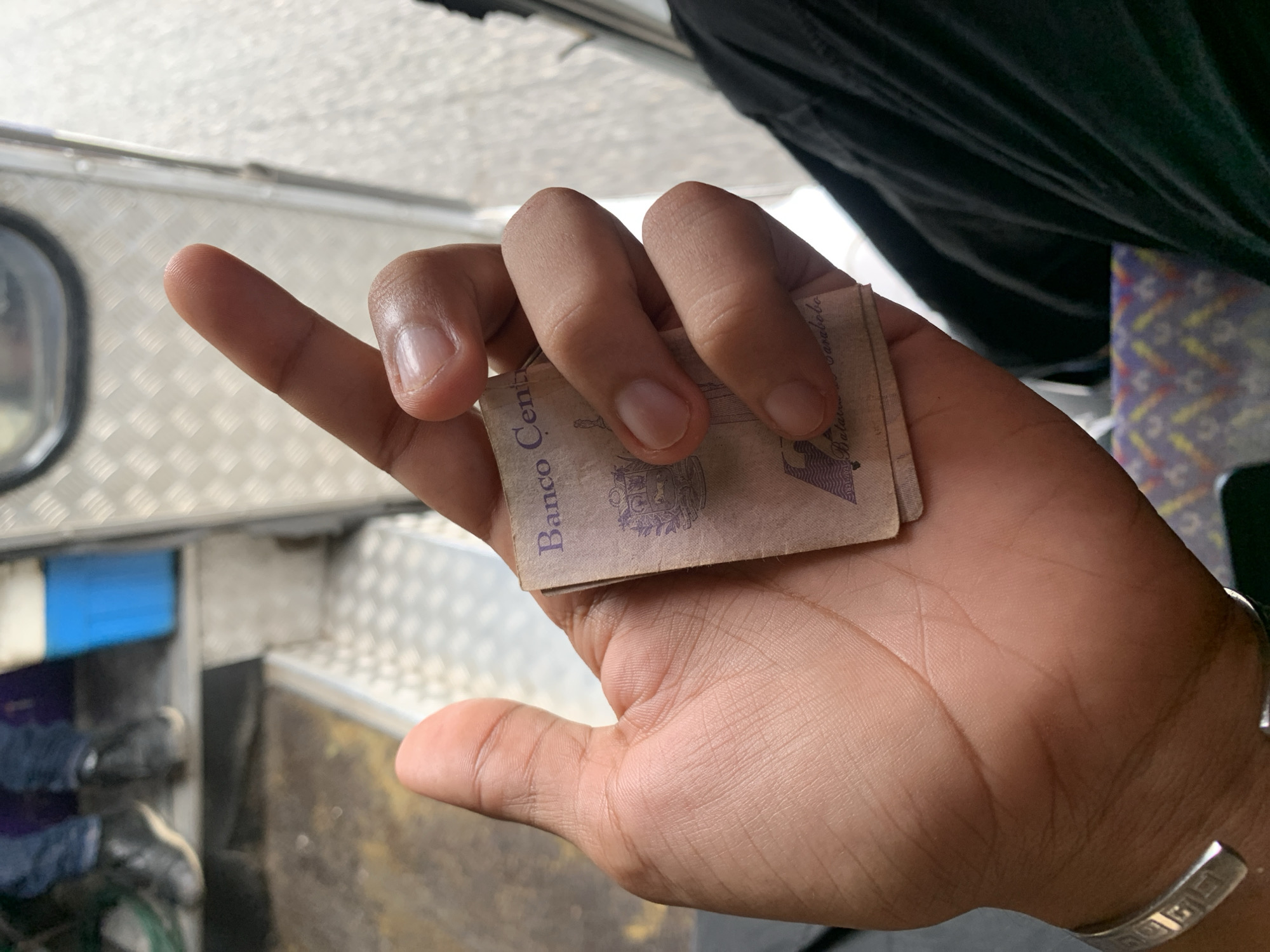 Person handles cash during vehicle journey in La Asuncion