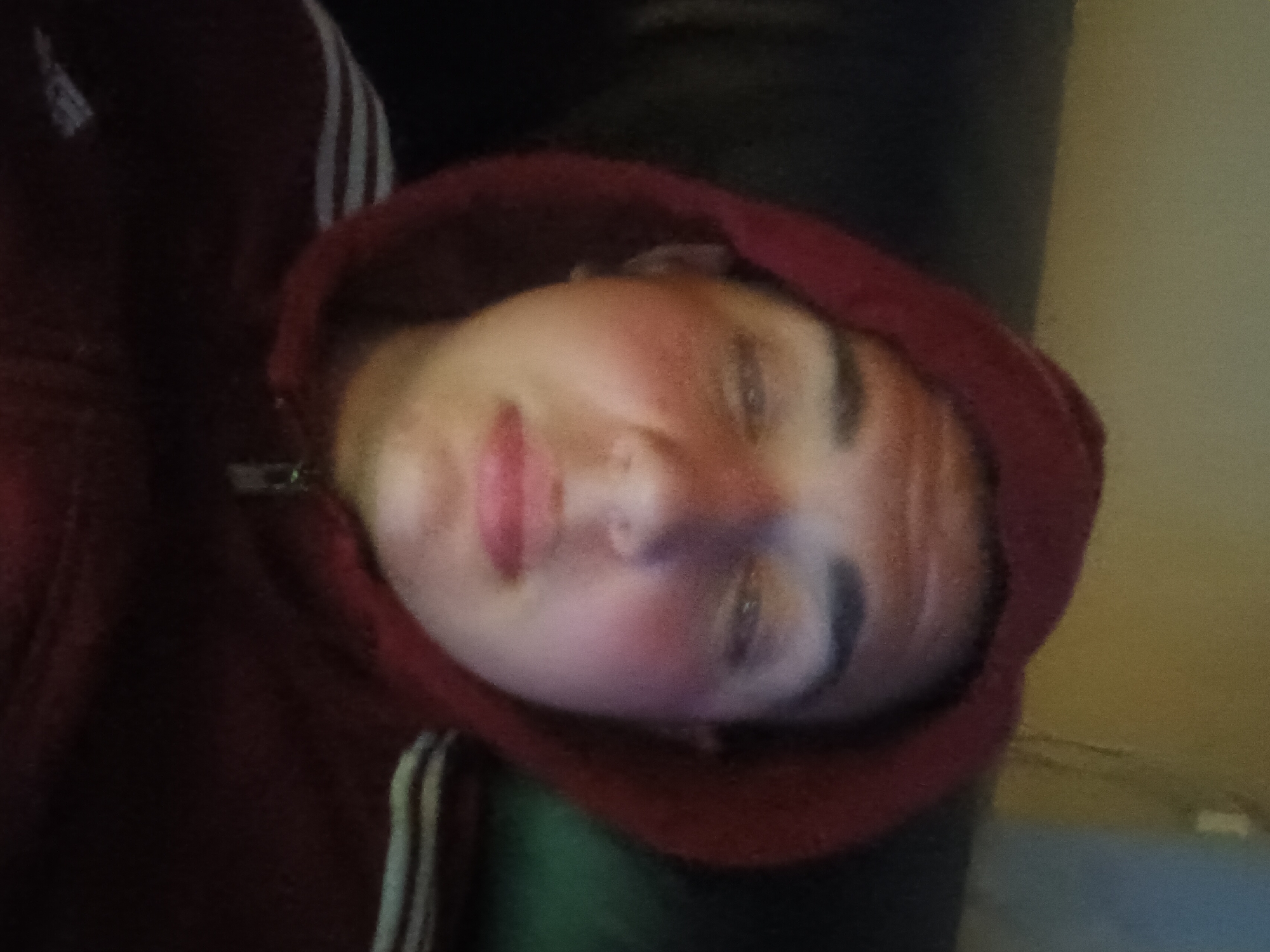 Person in Adidas hoodie rests on couch while using phone