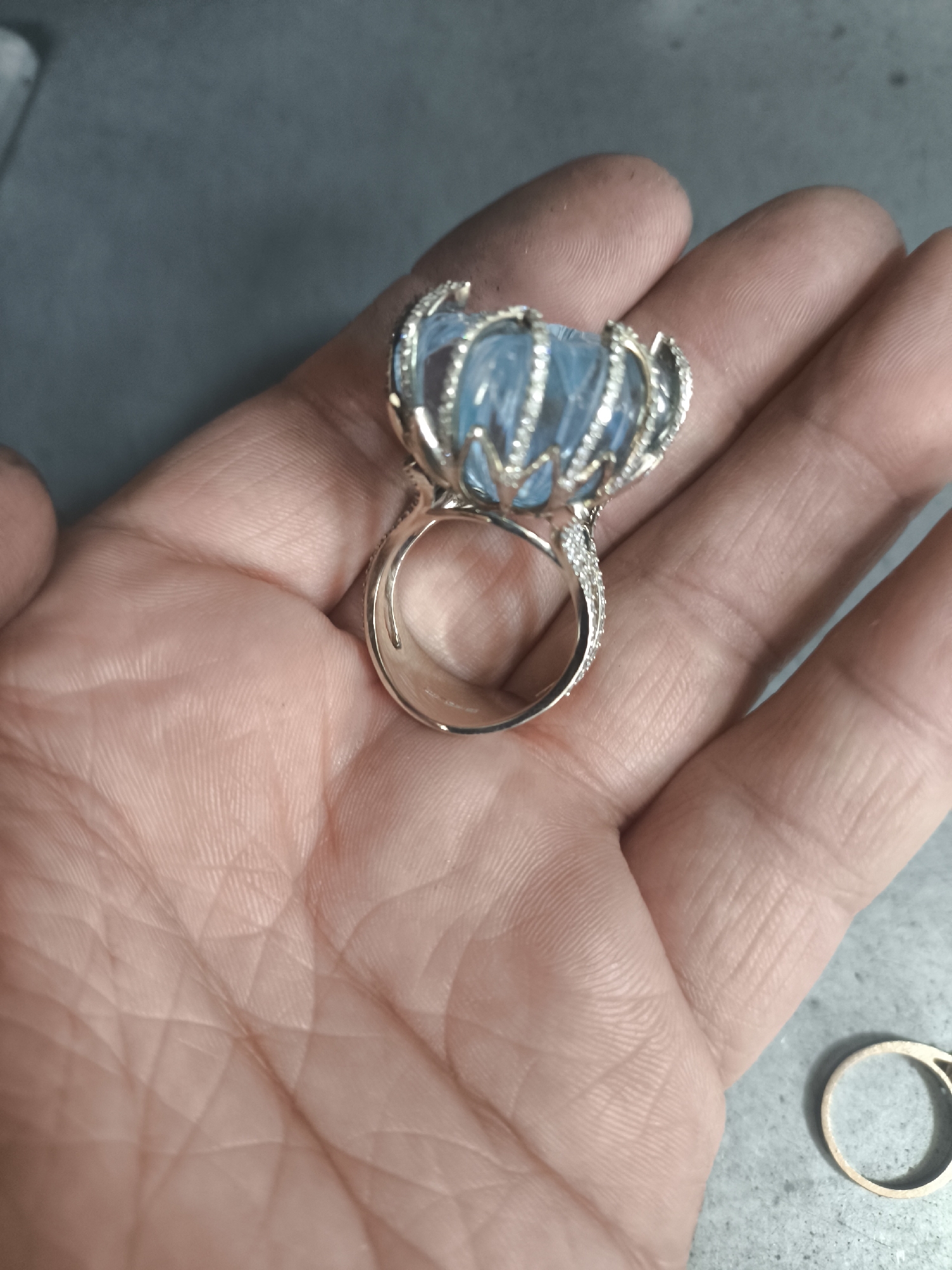 Ornate ring with light blue gemstone resting on an open palm