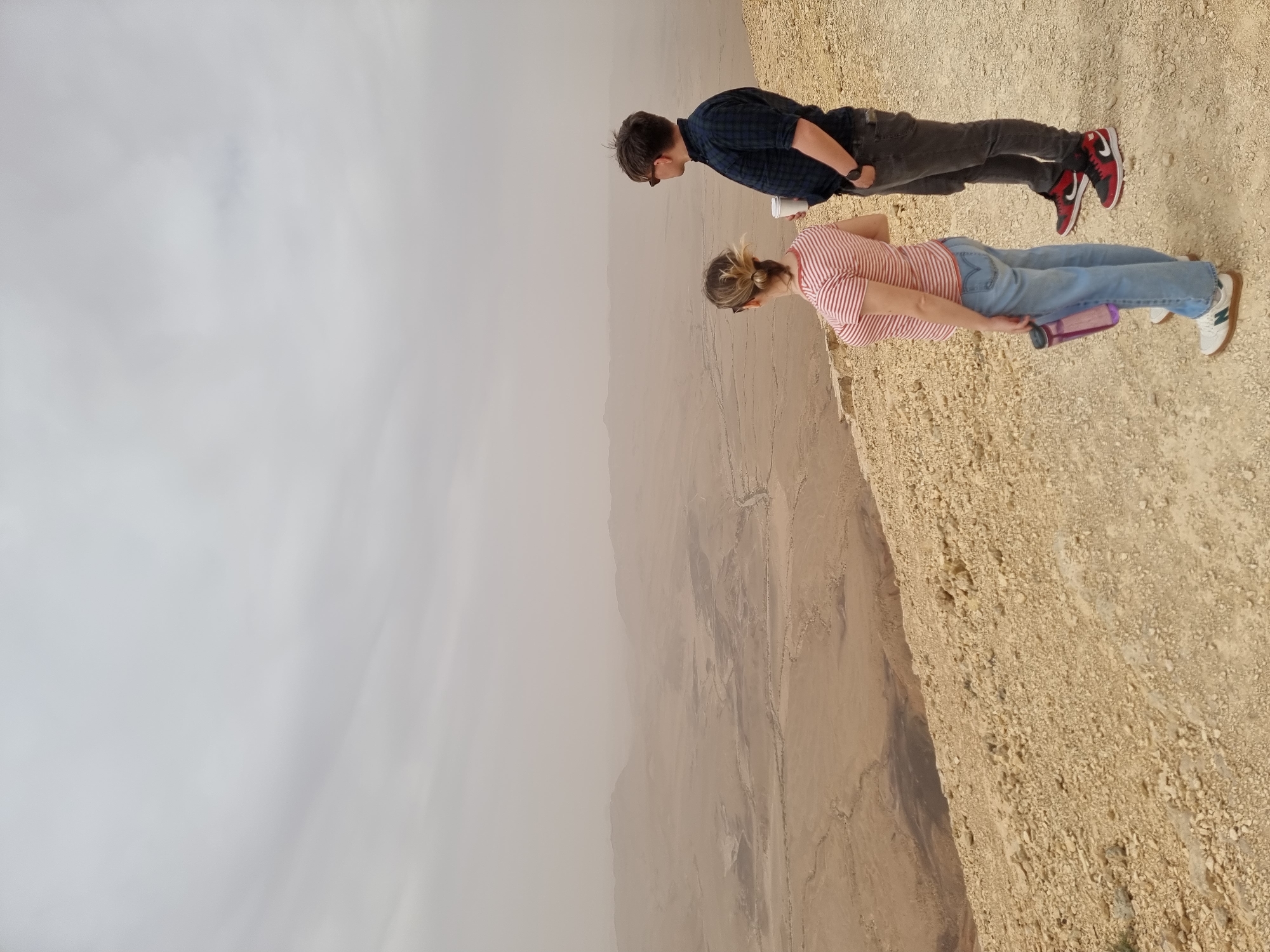 Two visitors observe desert landscape at Mitzpe Ramon overlook