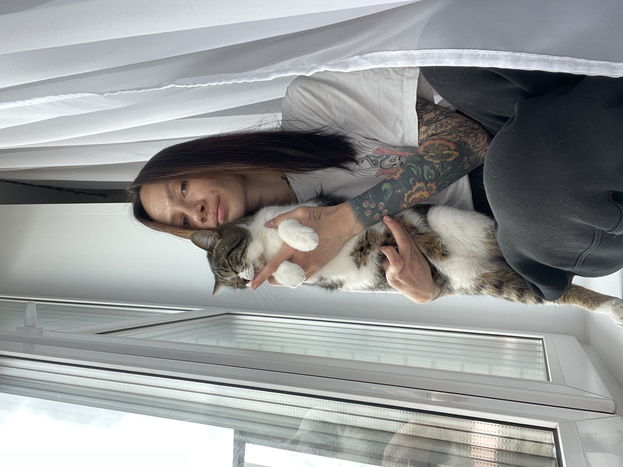Tattooed woman and tabby cat share quiet morning moments