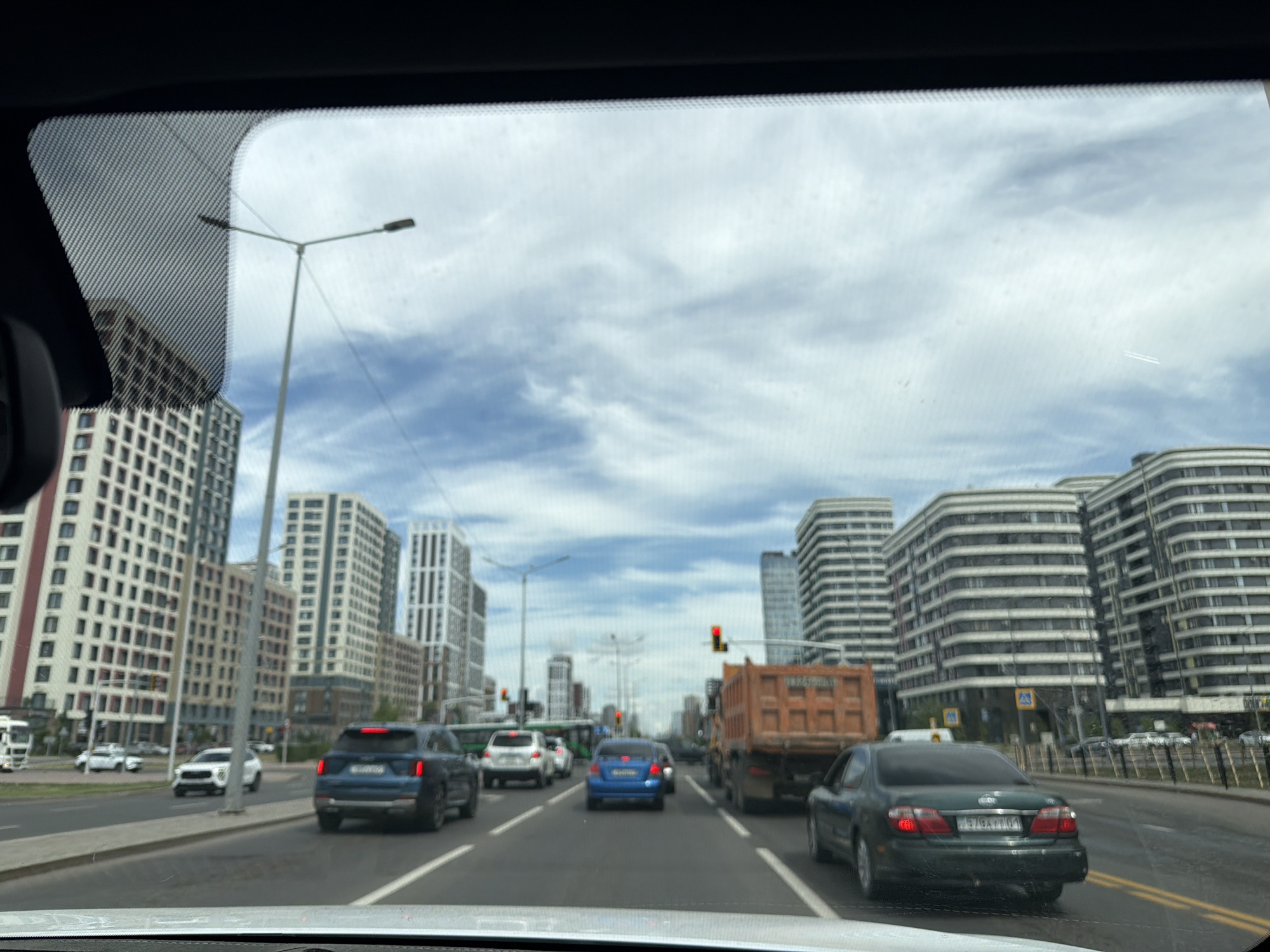 Modern Astana streets: glass towers, traffic, and a fitness club