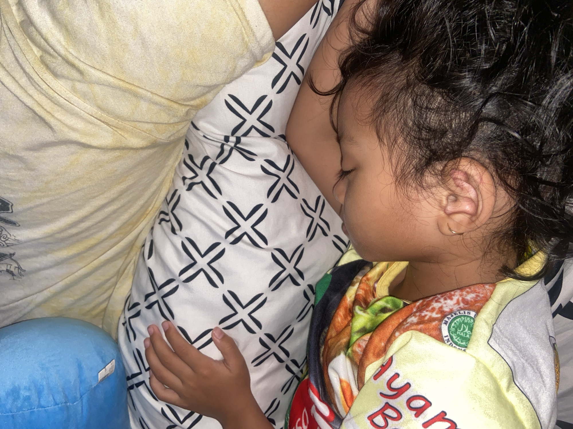 Child sleeps peacefully beside adult in Indonesian home