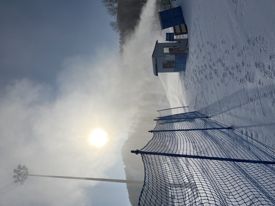 Snow cannons create artificial powder on sunny ski slope