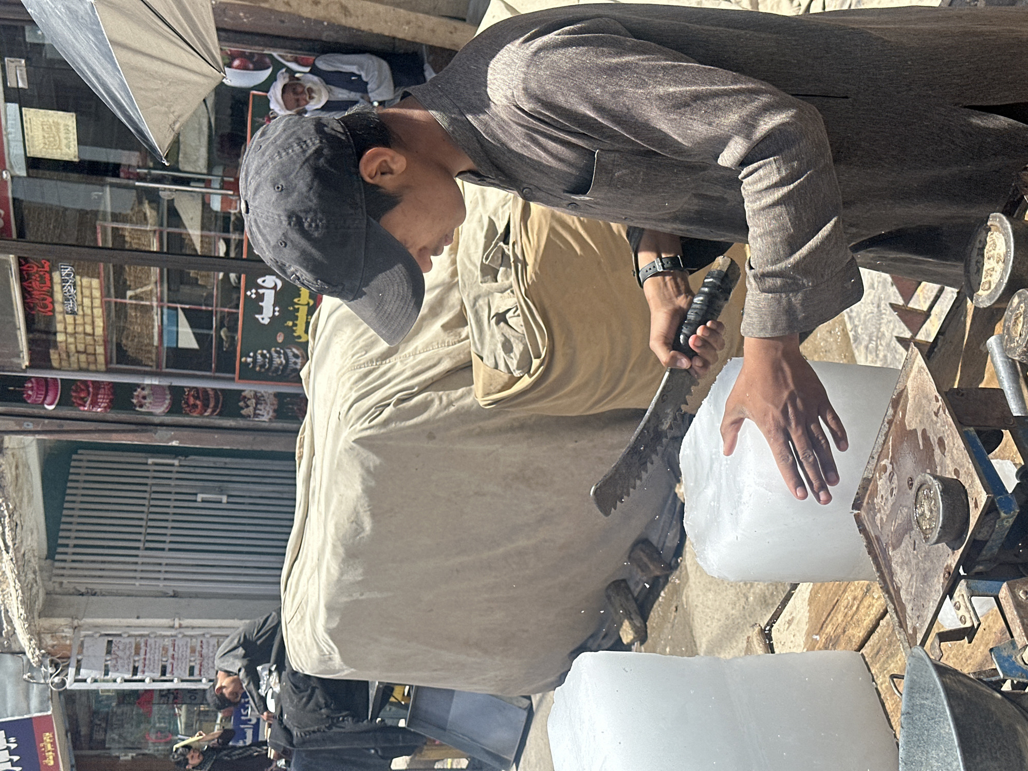 Man cuts ice block on busy Pishin street