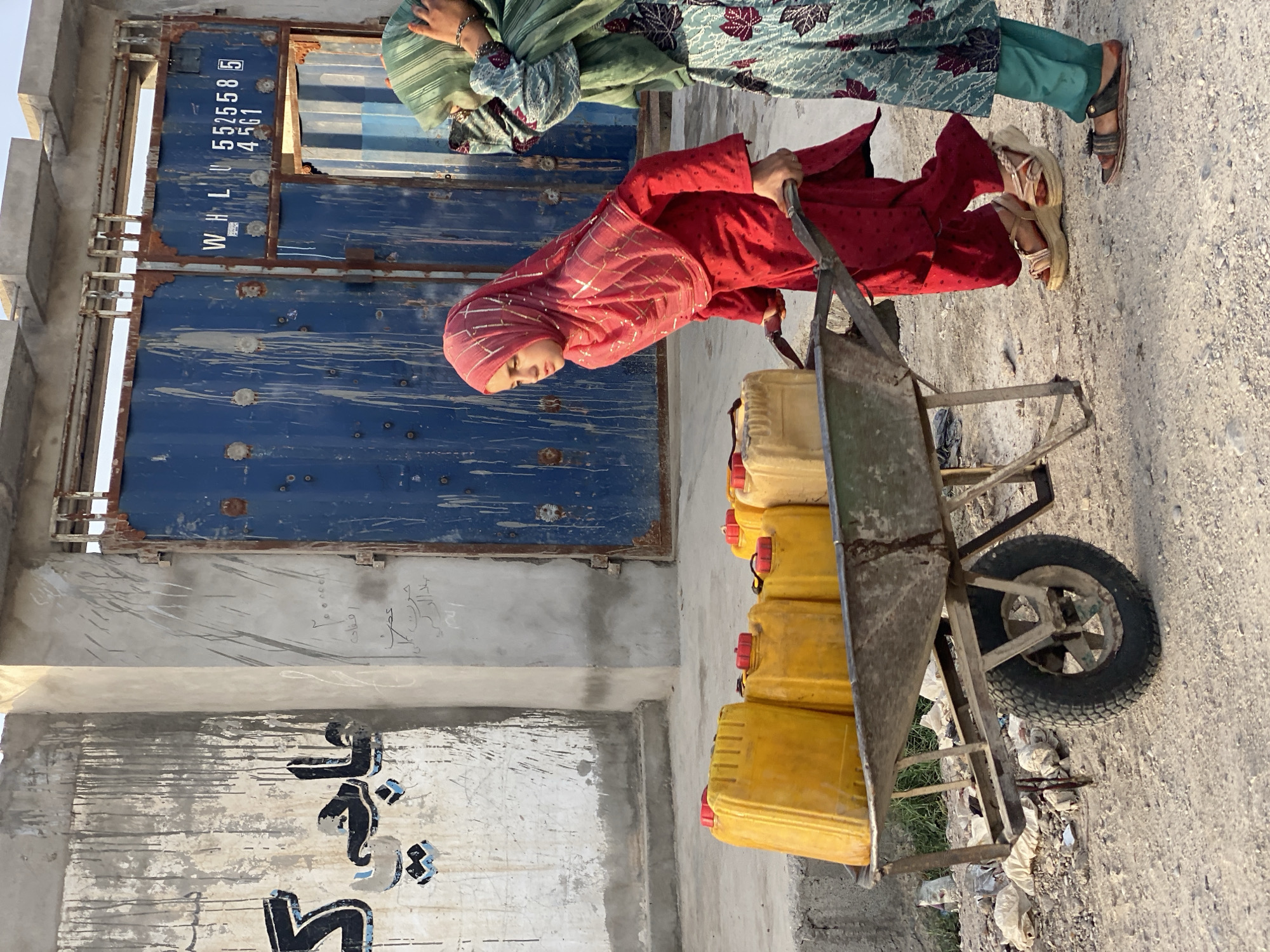 Hauling jerrycans by wheelbarrow through Kandahar streets
