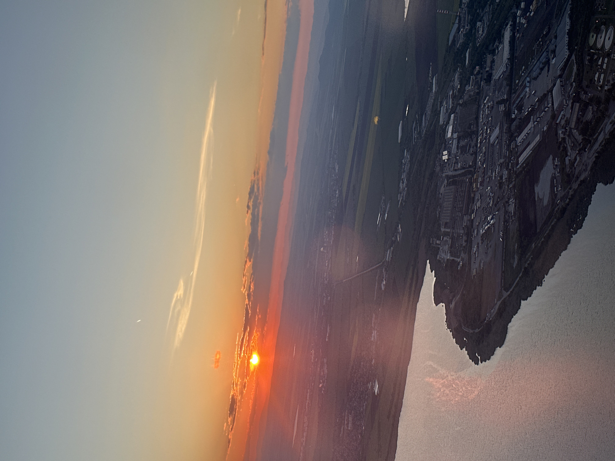 Sunset illuminates industrial waterfront area in aerial view