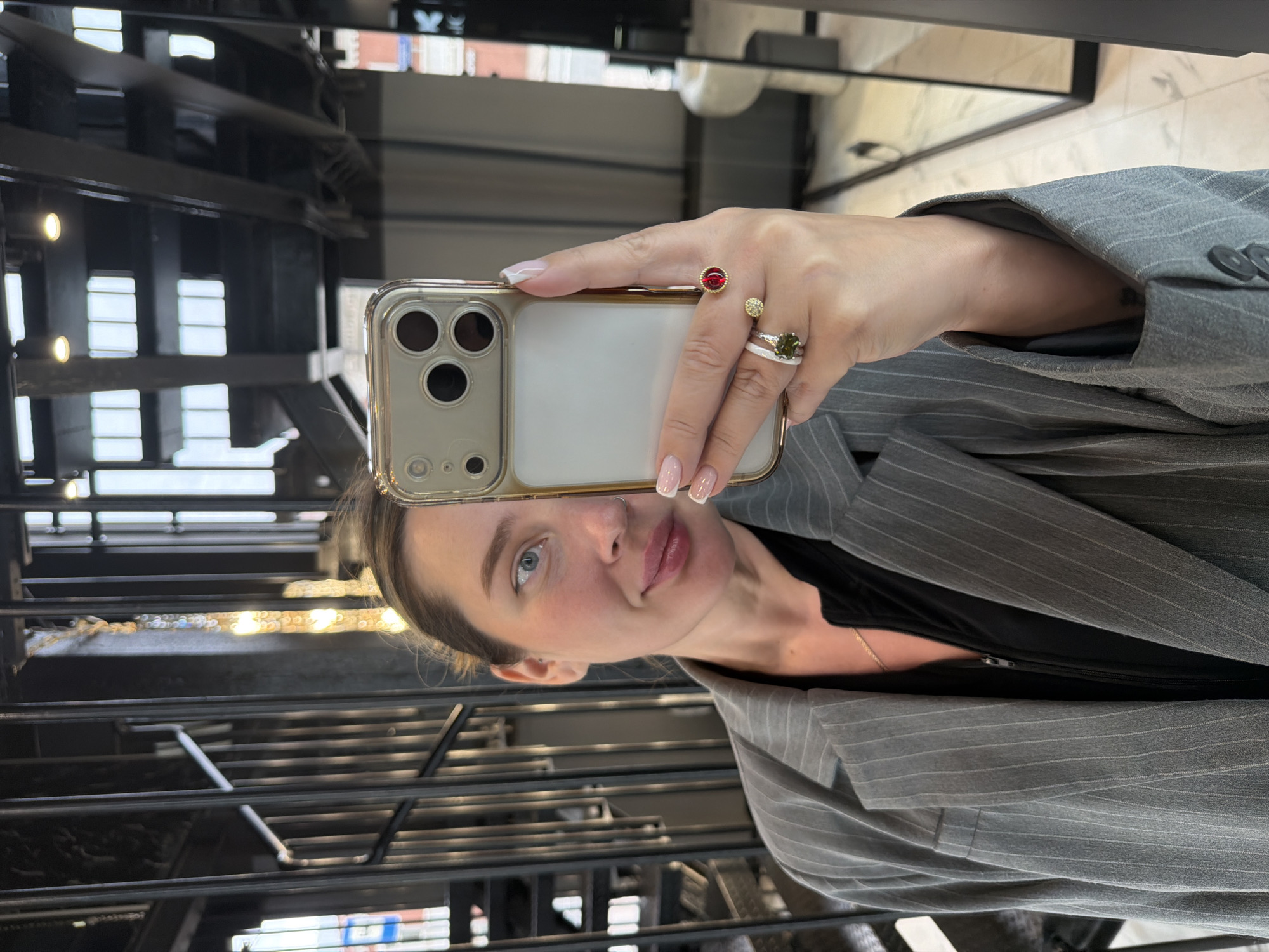 Woman takes selfies in indoor space with stairs, chandelier