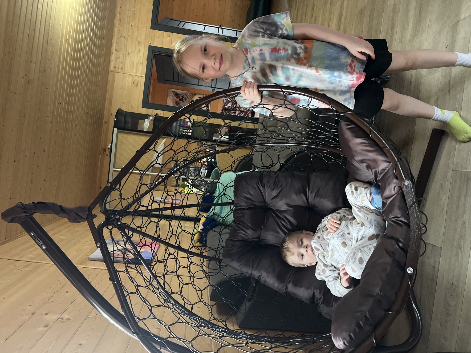 Children playing indoors with hanging chair in Protasy home