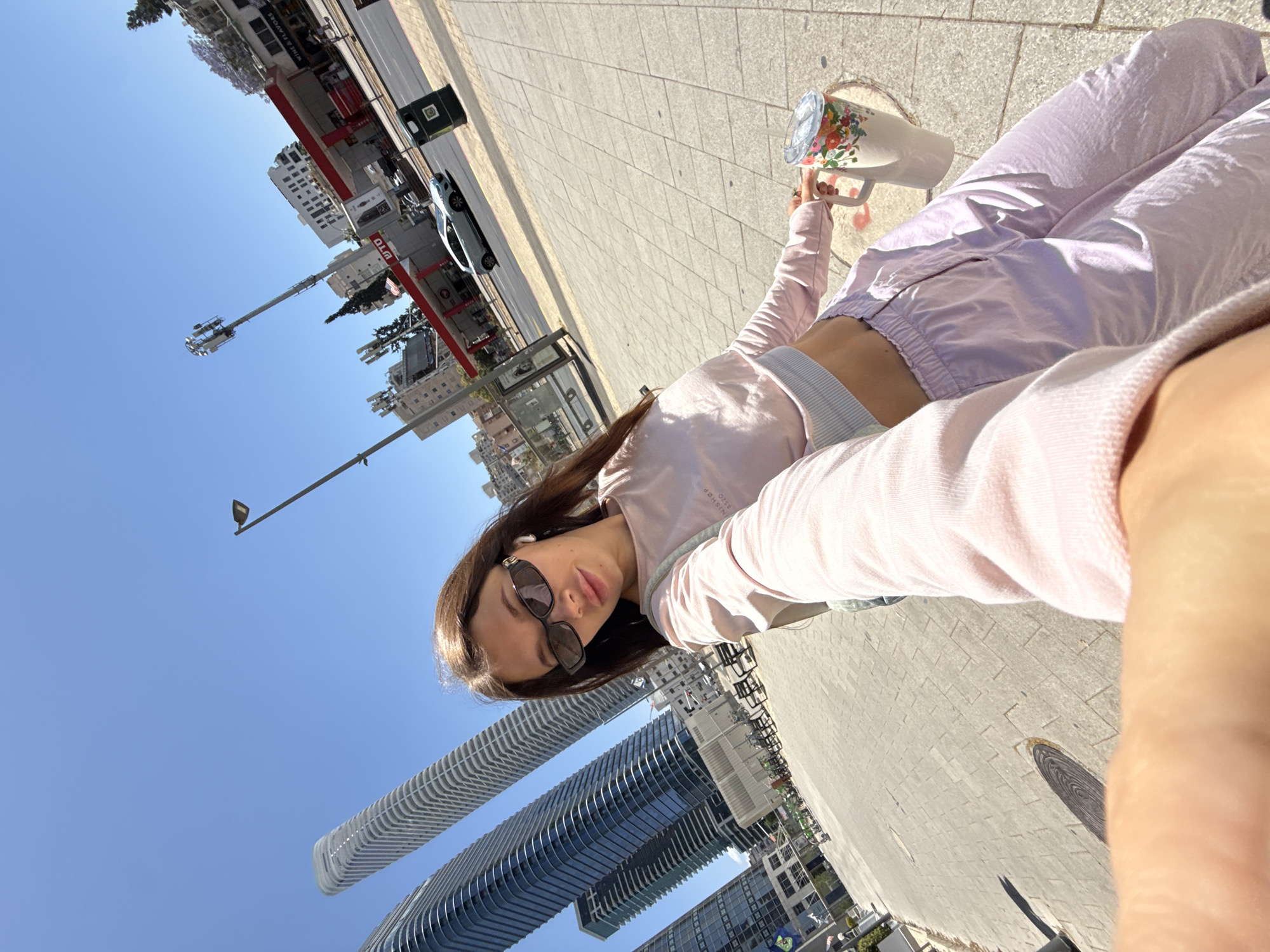 Woman takes selfie on Ramat Gan sidewalk amid urban backdrop