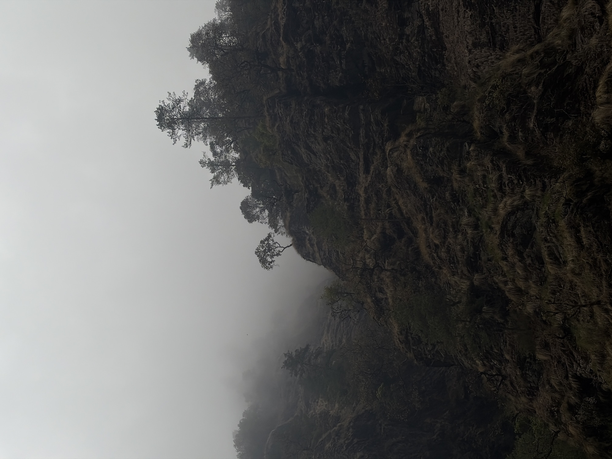 Fog shrouds dramatic cliff face in Dhunche, Nepal