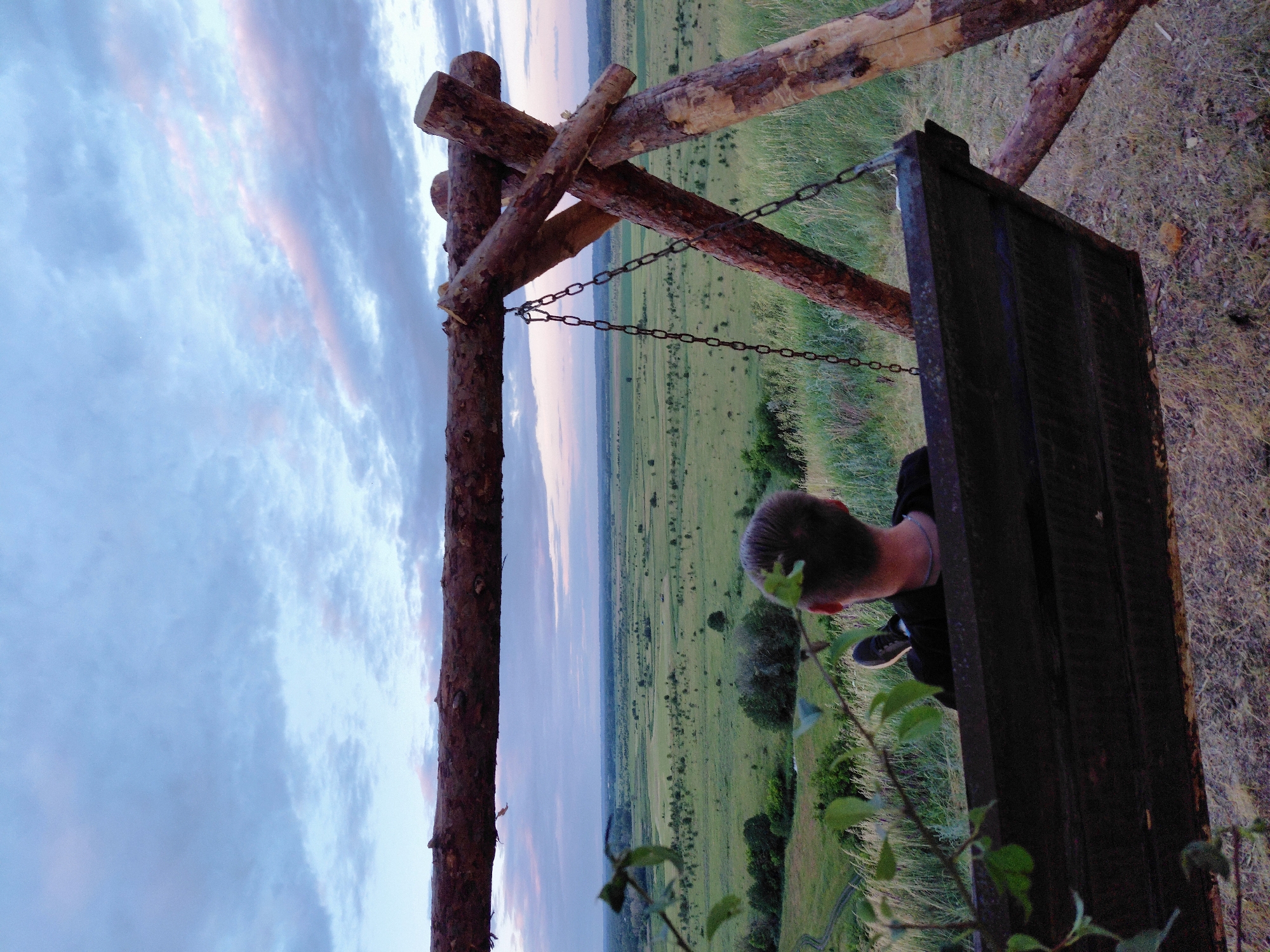 Dusk over open farmland, fields, and a hilltop swing