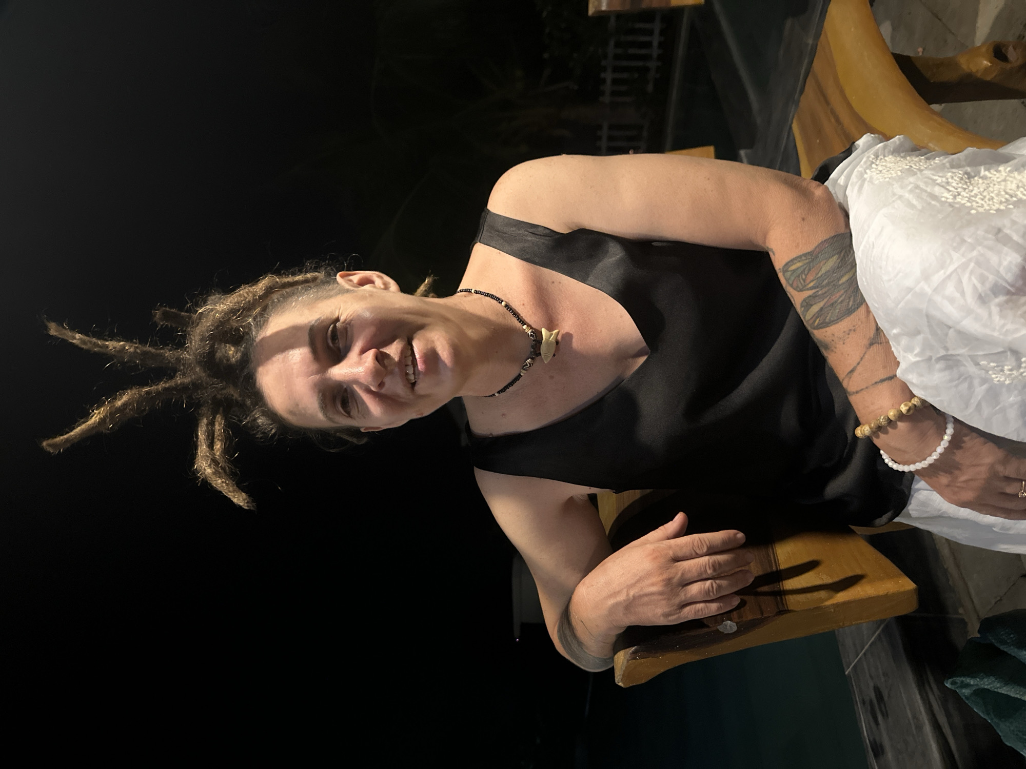 Person with dreadlocks relaxes outdoors with phone, rum in Mũi Né