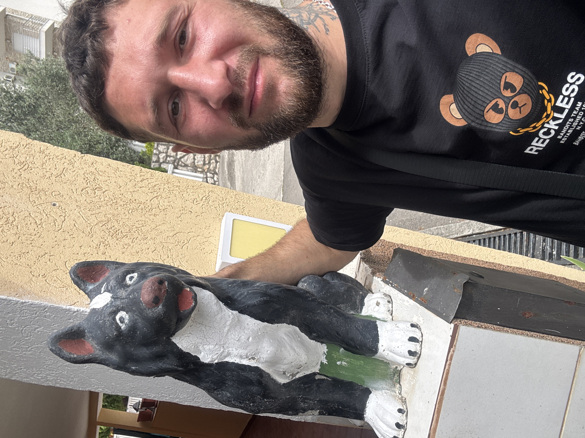 Man poses with dog sculpture in black T-shirt
