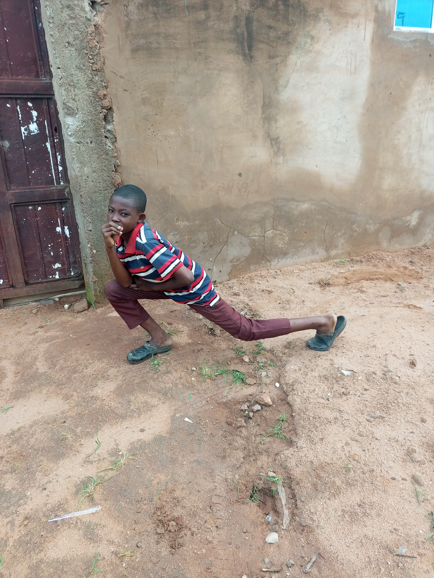 Striking a split pose outside a weathered door in Tempure