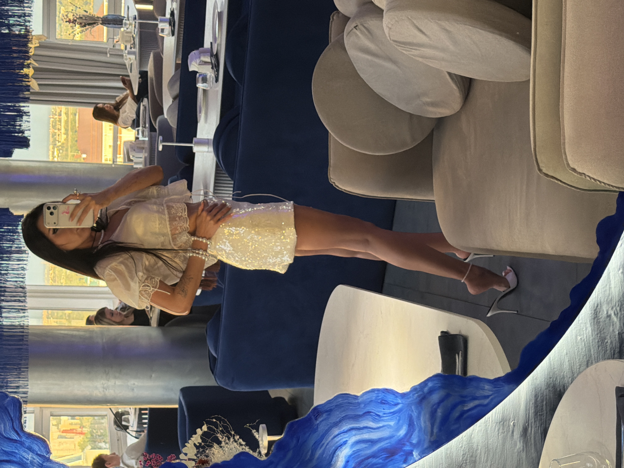 Mirror selfie in a blue-accented restaurant, all-white outfit