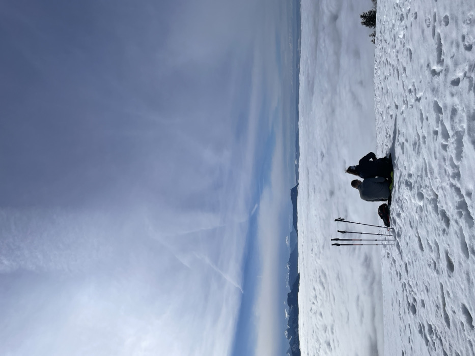 Two people sit on snowy ridge near Les Déserts