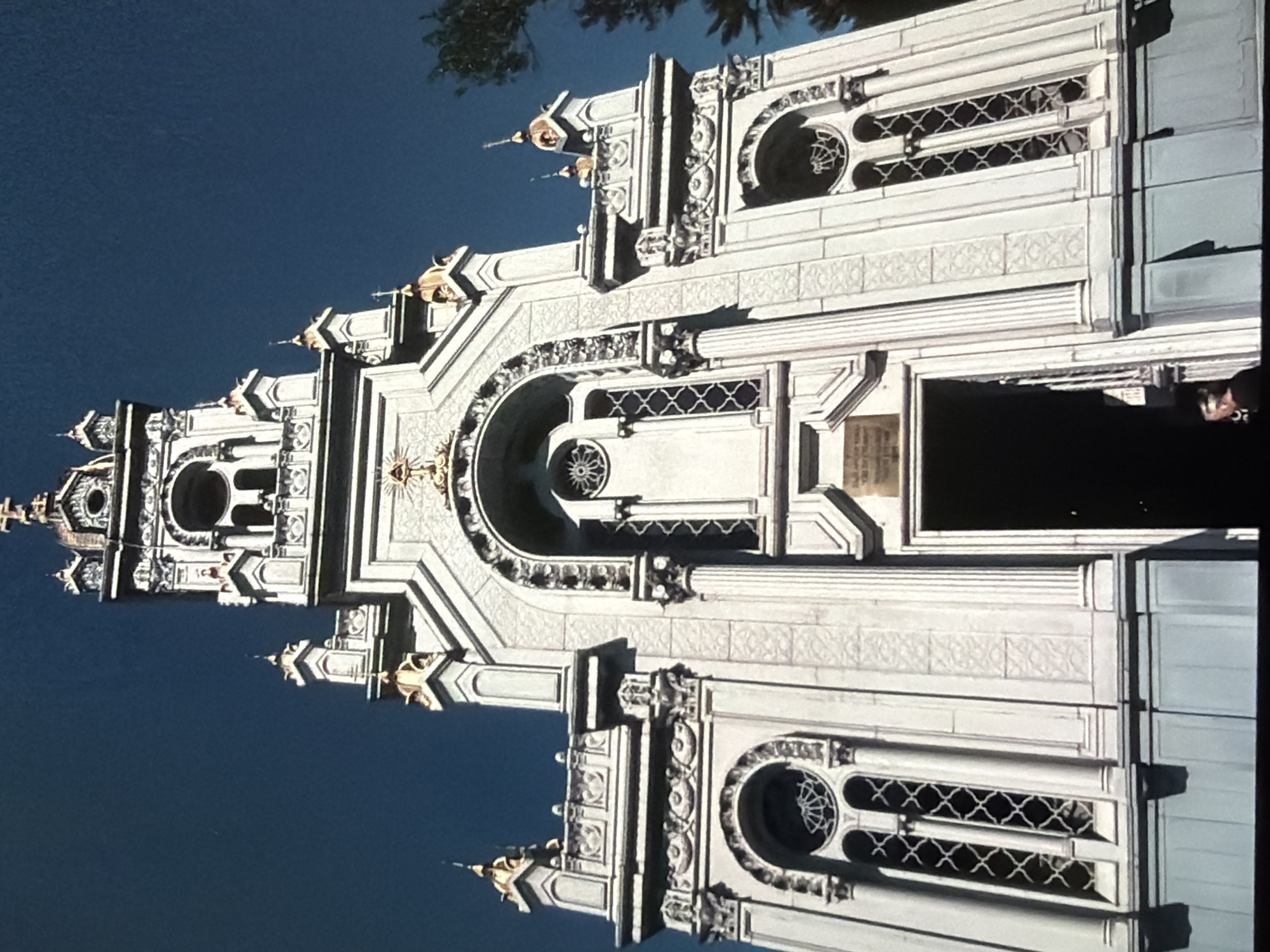 Looking up: ornate stone facade and a contrail-streaked city sky