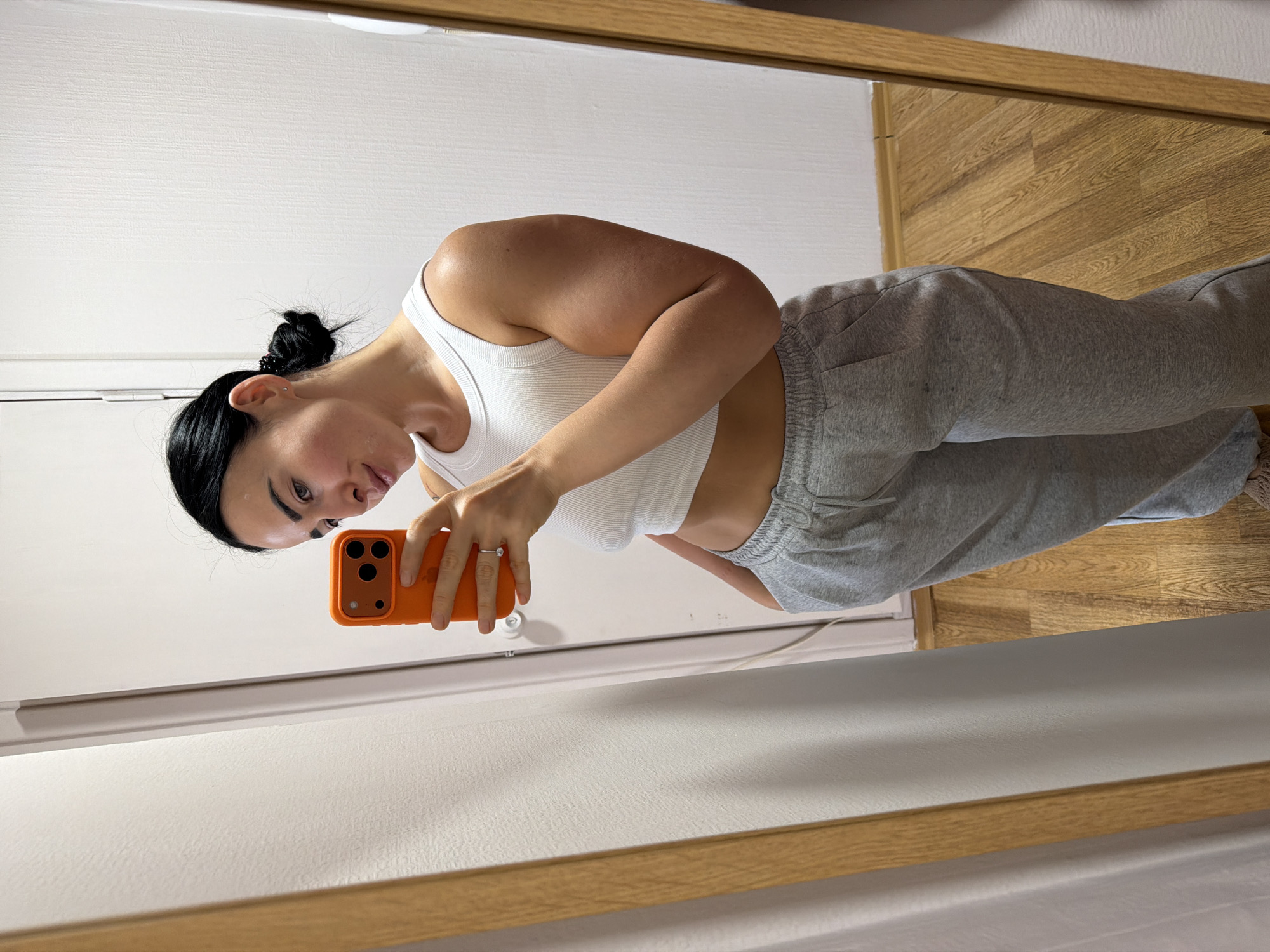Woman takes mirror selfies with orange phone indoors