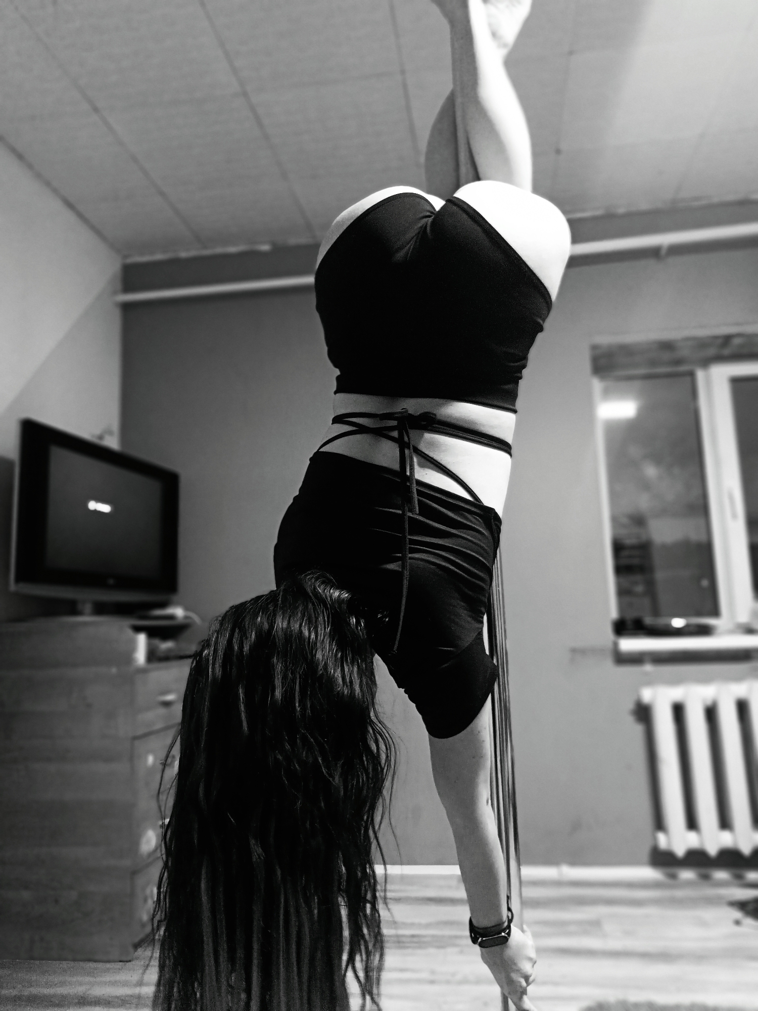 Woman practices pole dancing moves during indoor training session