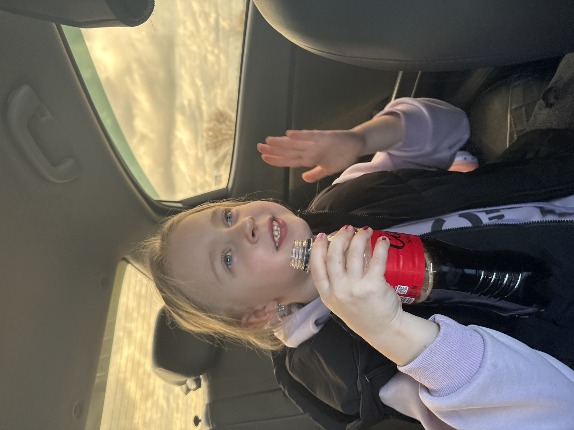 Child drinks Coca-Cola in car backseat in Kurganinsk