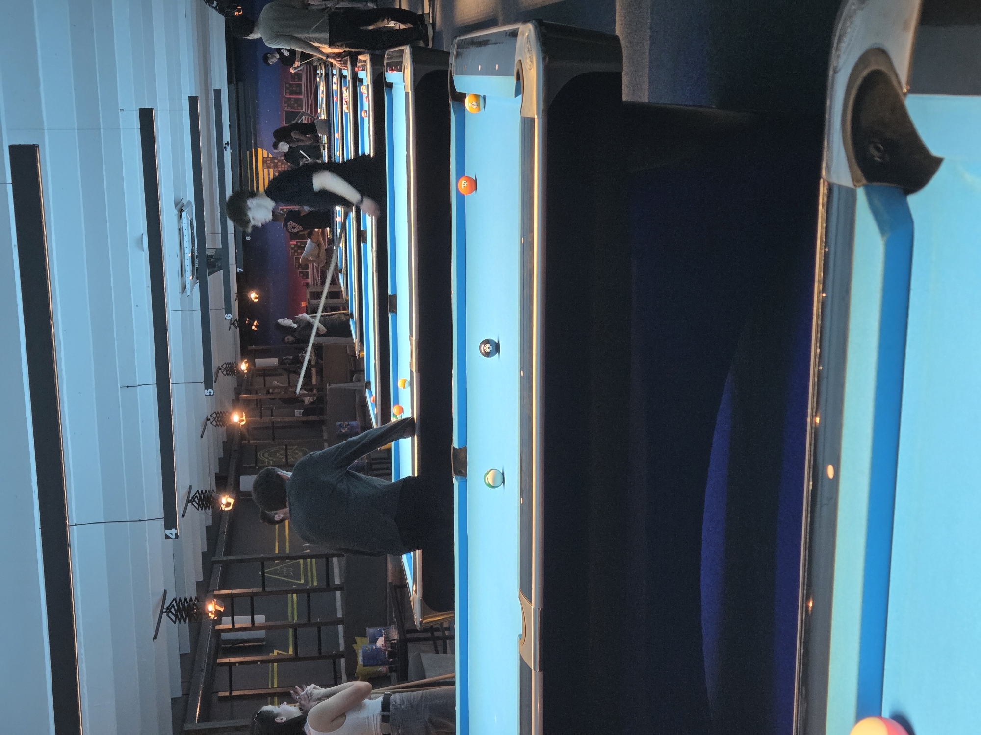 Pool hall buzzing with evening billiards games and spectators
